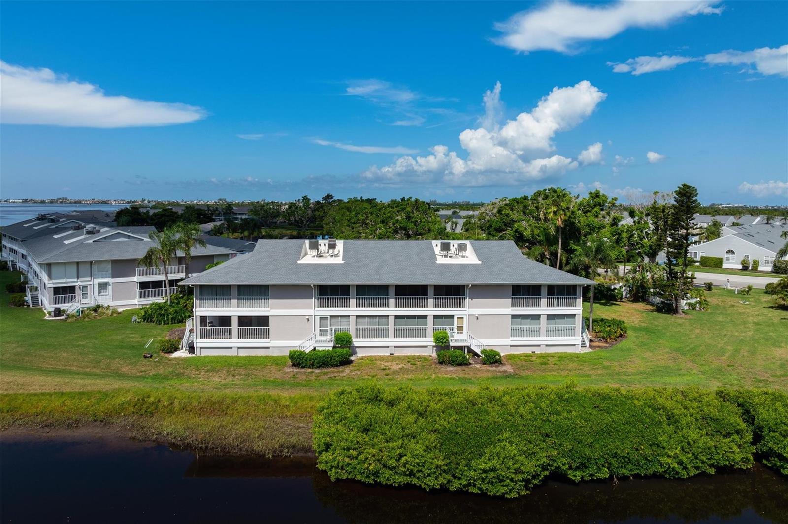Island Living at Its Best in the gated community of Perico Bay Club! NEW ROOF and NEW A/C. Welcome to this beautifully maintained second-floor end unit with expansive views of a peaceful lagoon and estuary, with Palma Sola Bay glistening in the distance. As the largest floor plan available in the community, this 3-bedroom condo offers spacious, light-filled living with vaulted ceilings and an open, airy layout. One of the bedrooms features charming barn doors and custom built-ins, making it ideal as a study, den, or guest space. The kitchen opens seamlessly to the dining area and includes a stacked washer/dryer for convenience. The primary suite is a private retreat, featuring a walk-in closet and a stunningly updated bath. Step out to the oversized enclosed lanai complete with a storage closet and enjoy birdwatching, entertaining, or simply relaxing while soaking in the tranquil water views. A shady side balcony adds additional outdoor space with views of lush greenery and water. Plantation shutters, and a new A/C make this unit move-in ready. A private 1-car garage is also included. This beautiful condo is offered unfurnished. Perico Bay Club’s gated community offers resort-style amenities, including an Olympic-sized lap pool, a clubhouse with activities, pickleball and tennis courts, shuffleboard, swimming pools. Enjoy kayak/canoe launches (including one just behind this unit), plus storage and a walking pier. Located just minutes from the pristine beaches of Anna Maria Island, Robinson ,Neal, and Perico Preserves ideal for biking and nature walks. Enjoy local dining and shopping, this villa is perfectly positioned for enjoying Florida’s coastal lifestyle. Schedule your private showing today and experience the charm of this waterfront gem in Perico Bay Club! All just over the bridge from Anna Maria Island. Come see it today!