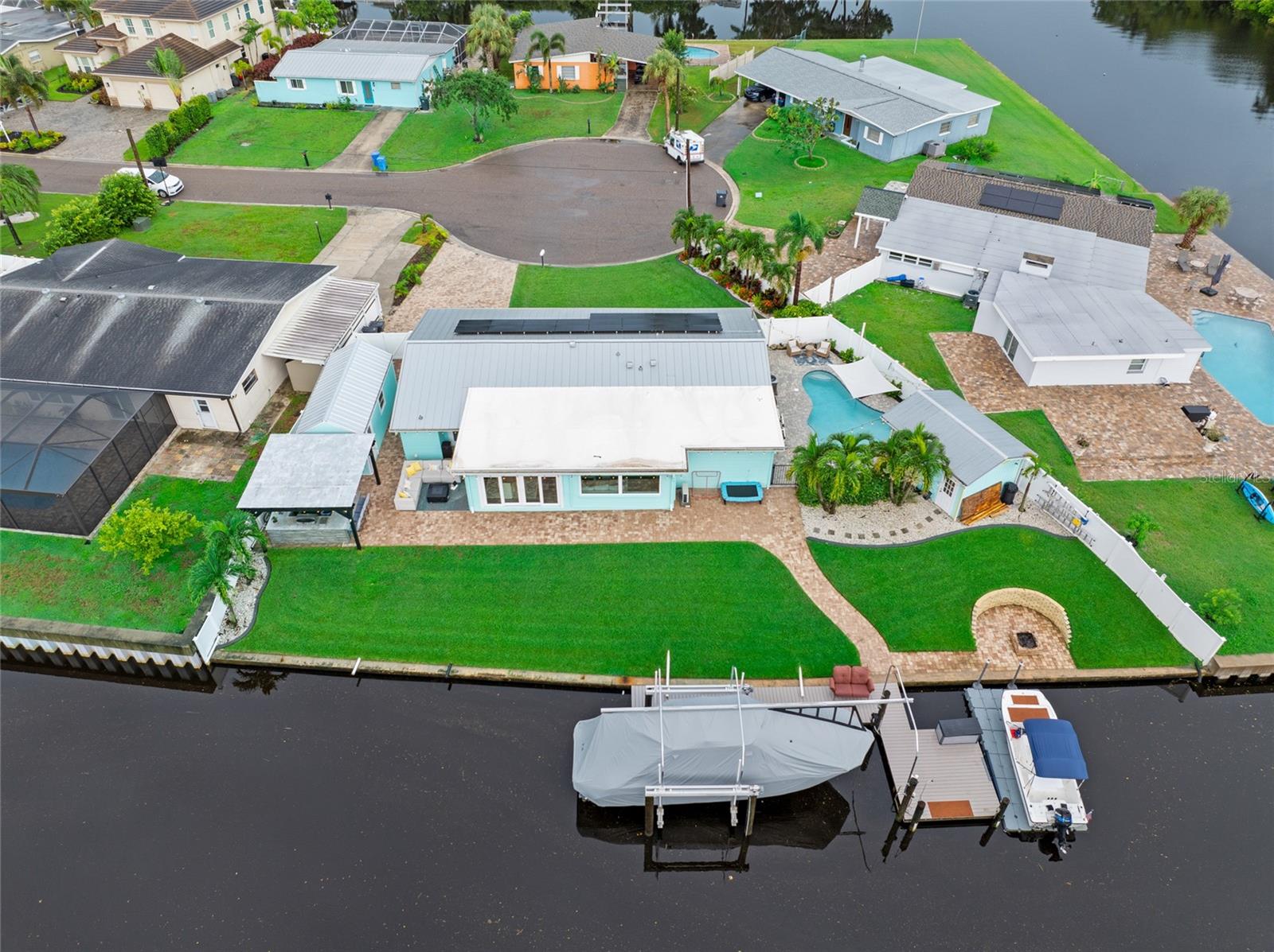 Experience the ultimate in Florida lifestyle with this 3 bed, 2 bath plus bonus room home on an oversized lot with 130+ feet of waterfront and direct access to Tampa Bay. Located at the end of a quiet cul-de-sac in the coveted Tampa Shores waterfront community, it offers privacy, luxury, and endless outdoor adventures. From the moment you arrive, the coastal charm is undeniable—wide paver driveway and tropical landscaping set the perfect tone. Inside, natural light fills the open layout, highlighting panoramic water views and stylish updates throughout. The remodeled kitchen features quartz countertops, stainless steel appliances, a hooded cooktop, soft-close cabinetry, and a breakfast bar, all flowing seamlessly into the great room with a plank ceiling, dual 62” fans, and built-in surround sound—perfect for entertaining or relaxing with family and friends. Step outside to your resort-style backyard. Lounge in the heated saltwater pool with LED lighting, sun shelf, and built-in barstools, entertain at the poolside cabana, or host unforgettable cookouts in the custom outdoor kitchen beneath a pergola. Gather around the waterfront fire pit as the sun sets over the bay. Dolphins and manatees frequently visit the waterway, adding a touch of magic to your outdoor experience. The 10,000 lb. boat lift easily accommodates midsized vessels, with water and electric for effortless boating adventures. The flexible bonus room doubles as an office, hobby space, or guest retreat with a built-in desk that converts into a Murphy bed. Two updated bathrooms feature modern tile, vanities, and fixtures. Additional upgrades include a metal roof, paid solar, impact windows, electrical enhancements, and whole-house bug spray system. Tampa Shores offers an optional HOA, neighborhood events, and a private community boat ramp, all just minutes from the airport, beaches, and waterfront dining. Live the Florida waterfront dream every day—schedule your private showing today!