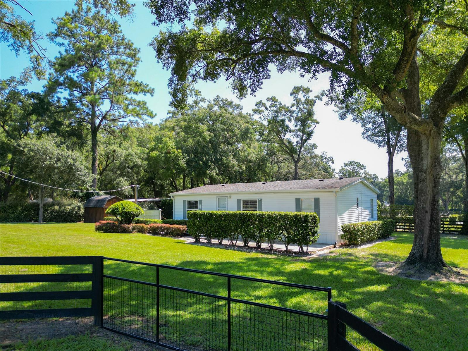 With huge income potential and a convenient location just 0.1 miles from HITS and a short drive from the World Equestrian Center, this beautifully maintained mini farm is purpose-built for equestrians looking to get the most out of Ocala’s Horse Country. Fenced and gated, the property features 3 acres that has been designed for ease of use by and for equestrians, all gently shaded by mature oaks. The 10-stall shedrow-style barn is thoughtfully outfitted with spacious feed and tack rooms, a covered wash rack, and a full bathroom and utility station complete with a refrigerator, microwave, and washer. Each stall is paired with its own paddock, while two covered grooming stalls and a tack room-adjacent lounge area provide added convenience and comfort for both horses and riders. A 100' x 175' arena is outfitted with clay fiber footing, providing plenty of space for training year-round. Those looking to accommodate long-term or seasonal renters will appreciate the four 50-amp RV hookups, each equipped with water, electric, and septic connections. A 24' x 16' equipment shed adds secure storage options for farm tools, large equipment, or tenant use. At the heart of the property sits a recently renovated 3-bedroom, 2-bathroom cottage offering approximately 1,080 square feet of light-filled living space. The open-concept great room flows effortlessly from the living area to the modern kitchen with stainless steel appliances, a breakfast bar, and a pantry. A convenient laundry area with a stacked washer and dryer sits just off the kitchen for everyday ease. The primary suite boasts a walk-in closet and a private en-suite bathroom with glass-door shower and generous counter space. For moments of rest and relaxation, a screen-enclosed patio with ceiling fans overlooks one of the nearby paddocks—perfect for quiet evenings after a full day in the barn. With a new roof installed in late 2020, this property offers peace of mind and immediate functionality, ready for horses, riders, and the season ahead!