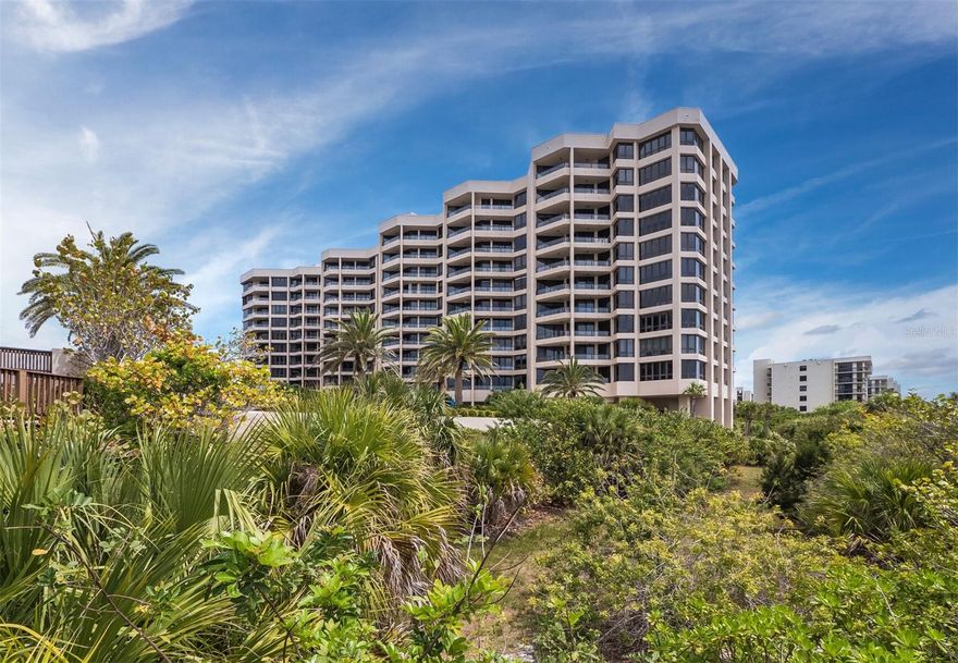 Set on the 7th floor of the Promenade on Longboat Key, this 2BR/2BA residence offers more than 1,800 square feet of living space with sweeping sunset views across the Gulf, stretching to Sarasota Bay and beyond. From the moment you step into the private entry foyer, the home opens to a light-filled interior where water and sky are always in view. Neutral tones and tile flooring create a clean, comfortable backdrop throughout, while the split floor plan provides privacy for both the primary and guest suites. The combined living and dining areas are oriented toward the Gulf, with a striking corner of windows and sliding glass doors that frame the shoreline, the community pool below, and the bay in the distance. The terrace naturally extends the living space—an ideal spot to unwind and take in the changing colors of the evening sky. The kitchen is spacious and thoughtfully designed, with stone countertops, detailed tilework, stainless steel appliances, and a casual eat-in area positioned to enjoy the view. A separate dining area, complete with a wine refrigerator, offers flexibility for both everyday meals and entertaining. The primary suite is generously sized, featuring a full wall of glass with direct terrace access. Two large walk-in closets provide ample storage, and the bath includes a soaking tub, glass-enclosed shower, and dual vanities. The guest bedroom enjoys its own views of both the Gulf and the bay, along with an en suite bath for added comfort. Additional highlights include an in-residence laundry room, secure building access, and one under-building parking space. Residents of the Promenade enjoy a full-service lifestyle with concierge, 24-hour security, a newly renovated lobby and common areas, two fitness centers, club rooms, four Har-Tru tennis courts, a heated lap pool, spa, and nearly 400 feet of beachfront. The location offers easy access to the shops and dining of St. Armands Circle, blending convenience with a relaxed coastal setting. Membership to the Longboat Key Club is optional and available to residents, offering access to an array of resort-style amenities. These include 45 holes of championship golf, award-winning tennis facilities, a full-service spa and fitness center, multiple waterfront dining venues, a private beach club, marina, and a calendar of social events and activities.
