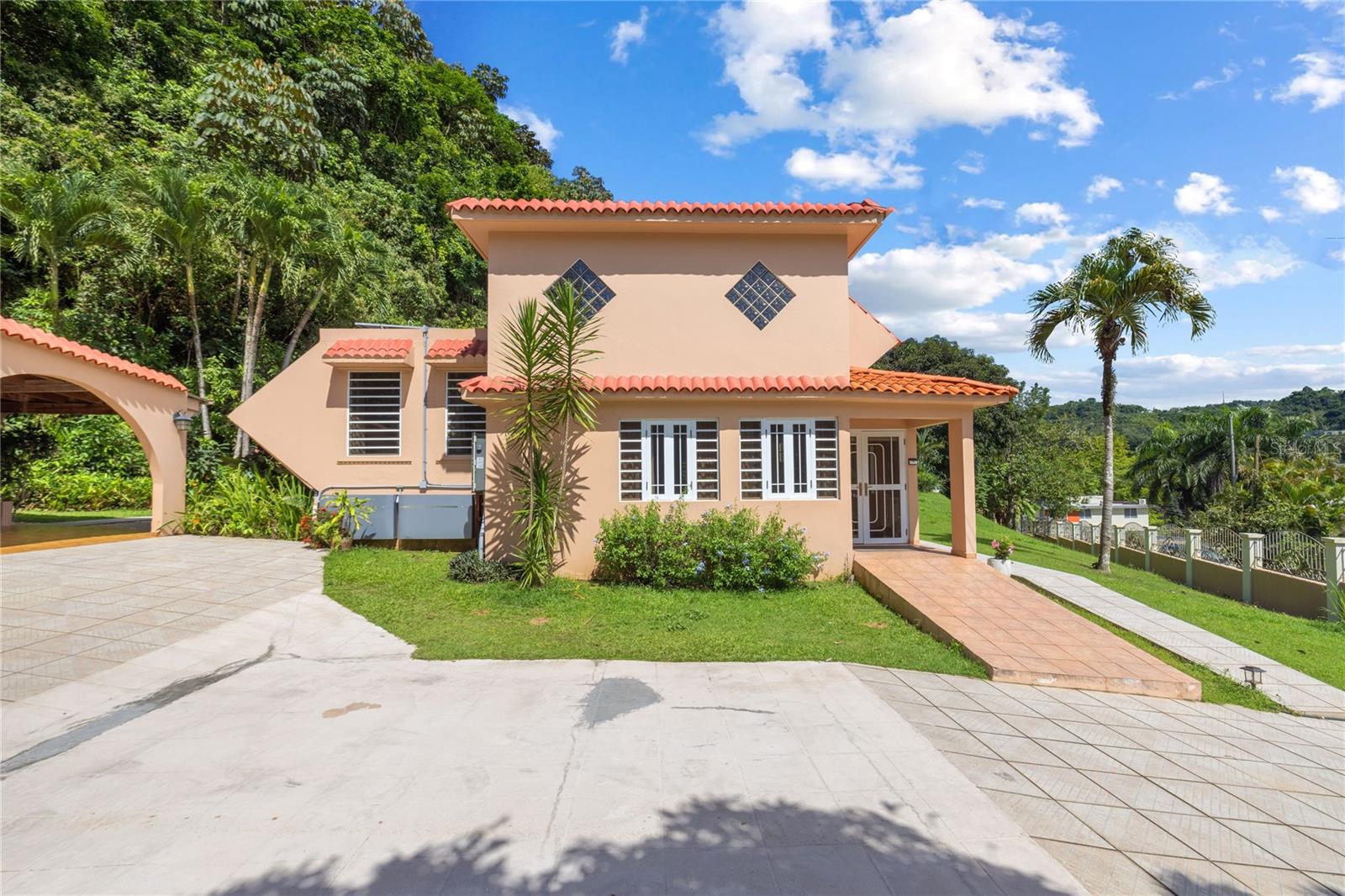 Tropical Investment Oasis in Guaynabo – Fully Furnished & Solar Powered
Welcome to your dream retreat in the private, gated community of Lomas del Sol, Guaynabo. This income-generating estate blends tropical living with smart investment potential — live in one unit, rent the other, or lease both for maximum return. Experience total privacy in a hidden jungle hillside retreat with breathtaking views of the natural landscape. This pristine property offers serenity and seclusion, while still being minutes from shopping, dining, and key attractions.
Featuring 5 bedrooms, 3 full bathrooms, and 2 half baths, this spacious two-level layout is perfect for multigenerational living or short-term rental income.
• Main level: 3 bedrooms, 1.5 baths
• Lower level (currently an Airbnb): 2 bedrooms, 2 full baths, private entrance, and kitchenette
• Additional half bath next to laundry area / carport structure
Outdoor Highlights:
• Resort-style circular pool with tile accents
• Covered terraces, gazebo, and outdoor kitchen with BBQ area
• Outdoor gym surrounded by lush greenery
• Gated driveway, ample parking, and immaculate landscaping
• Fruit trees on site: mango, avocado, banana, and pineapple
• Magical nighttime ambiance with coqui frogs under the stars
Upgrades and Features:
• Solar panels and water cistern for self-sufficient living
• Mini-split AC units throughout
• Fully furnished – turnkey ready
• Laundry room
• The lower-level unit maintains a strong occupancy rate and consistent income through Airbnb.
Living Area: 2,142 sqft | Lot Size: 2,336.90 m² / 0.577 acres | HOA: $27