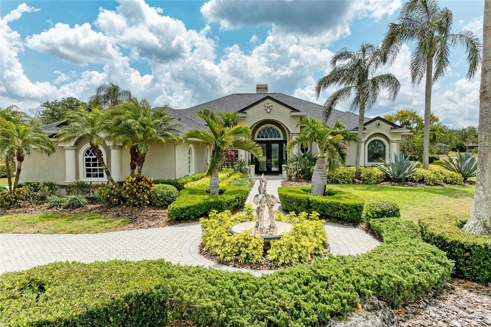 Price Reduction and New Roof! Discover elegance in this custom 4 bedroom, 3 1/2 bath dream home with panoramic views of River Club Golf Course. This stunning home with a 3-car garage is surrounded by lush, mature tropical landscaping. Embrace timeless luxury and modern convenience as you step through the double glass doors with sidelights onto Travertine tile. Enjoy awe-inspiring views of the living and dining rooms, enhanced by 12 ft coffered ceilings, crown moldings, and a spectacular gas fireplace. This entertainment area connects to a wet bar with custom glass cabinets and a wine cooler. The island kitchen is a chef's delight, featuring stone countertops, stainless steel appliances, stepped wood cabinets, and pendant lighting. A cozy breakfast area with bay windows overlooks the lanai. The family room with wood floors, decorative tray ceiling, and 28 ft of disappearing sliders creates a seamless blend of indoor and outdoor living. Enjoy a cinematic experience in the fully furnished media room with 2 level seating, a 100-inch projection screen and surround sound. Additional speakers are found through-out the house, lanai & sundeck. Retreat to the elegant primary suite with tray ceilings, French doors opening to the verandah and a versatile bonus room. The luxurious bathroom includes an elevated tub, dual sinks, & walk in shower. On the far side of the house a guest room provides access to a private outdoor patio. 2 additional bedrooms provide ample room for family and friends. Relax or entertain in the heated pool & spa with multilevel fountains & waterfalls. The expansive lanai features 2 verandahs with custom wood ceilings. One has a built-in grill, storage cabinets and an outdoor shower. The other has a built-in bar area with sink and refrigerator. To the side of the lanai enjoy an open sun patio or in the backyard, a beautifully landscaped tropical patio adjacent to the golf course. This home comes with 2 AC units, 2 water heaters, central vac, Radiant Barrier in the attic, underground 250- gallon propane gas tank & underground well for irrigation. A short drive will get you to shopping, restaurants, theater, and medical facilities. This home comes with a NEW ROOF & the confidence of a HOME WARRANTY. Enjoy the virtual tour with a 3D Matterport!D