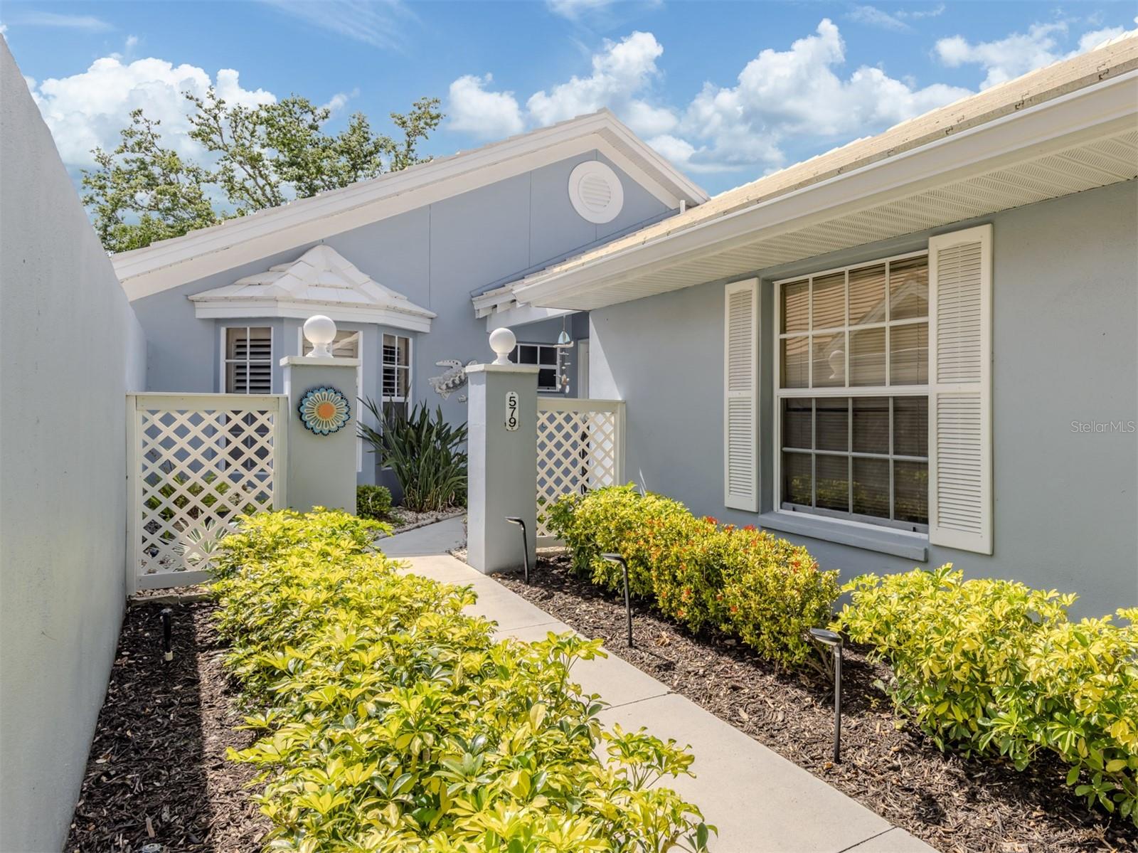 Golfers, tennis and pickleball players, swimmers, and/or all just seeking to relax, this complete turnkey listing is not to be missed. A beautiful, bright and spacious two-bedroom plus a bedroom or den, free-standing villa with a two-car attached garage is move-in ready! The garage has a number of cabinets, a work bench and a large modern second refrigerator. Feel comfortable with a new air-conditioner, recent (2017) roof and a hurricane-impact door that opens from the kitchen to the newly paver extensive patio holding tables, chairs and grills. The ceramic tiled kitchen has modern appliances, including a recent Bosch dishwasher, solid Corian counters, a food-prep island and complete cabinetry holding utensils, dishes, towels, napkins, along with a well-lit breakfast nook. The open and spacious, high ceiling furnished dining/living area is ideal for entertaining. The west-facing Florida room, surrounded by large sliding doors, overlooks a substantial pond, fountain, mature plantings and beautiful trees. Sunsets from this room, which holds a full-sized sleeper sofa, are a delight to experience. The large primary bedroom suite, with a substantial closet, has a bay window overlooking the pond. The windowed primary bath has a large shower with bench, and a dual vanity sink counter and a large walk-in closet. The guest bedroom has a large bay window and en-suite bath that has a shower with tub and window as well as a fully stocked linen closet. The third bedroom or den has cabinetry with built-ins for a dresser and desk along with a light-filled atrium which holds outdoor plantings that can be seen from another full-sized sleeper sofa in the room or from the main living/dining area. In the popular gated, maintenance-free community of Clubside Villas at the Plantation, with its clubhouse and completely refurbished (2022) heated saltwater pool, this home is immediately adjacent to the Plantation Golf and Country Club, with two 18-hole golf courses, tennis courts, pickleball courts and many other activities. Optional memberships are available. Nearby is Wellen Park with new shops, restaurants and the spring training home of the Atlanta Braves at Cool Today Park. Also nearby is the city of Venice's shopping, restaurants, beaches and water sports. Don't miss this light-filled residence. Just bring your toothbrush.