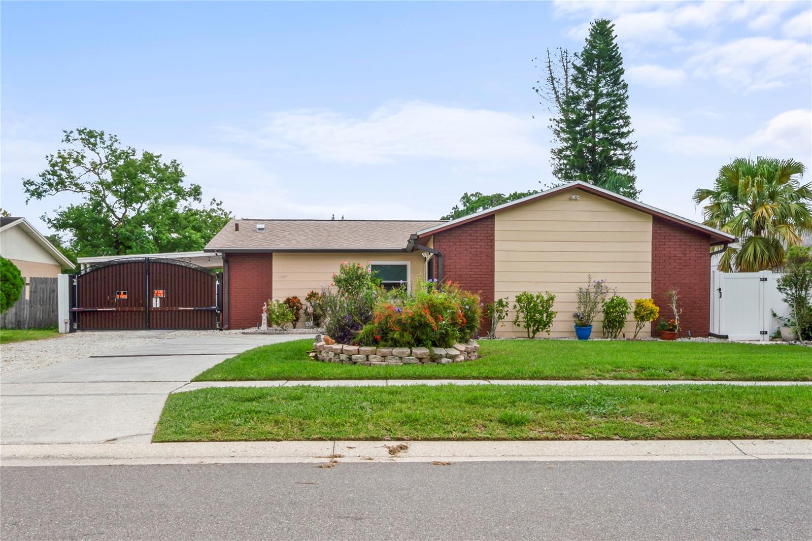 As you pull up to this beautifully maintained three bedroom and two bathroom home you will first notice the care the owner has put into her yard and plants. A well maintained one car garage that will help keep your car looking fresh from this Florida sun. The owner has put a lot of pride and care into this home starting back in 2008 with an upgrade to the kitchen. The kitchen cabinets were refinished in 2018 giving them a newer and more modern look. The AC was replaced in 2017. Hurricane fold-in windows were added in 2020. New gutters were installed in 2021 along with a new water heater. A vinyl fence was installed in 2022. The garage door screens were replaced in 2022 giving you the possibility of enjoying your garage away from the sun and keeping the bugs out. The roof was also redone in 2022. A generator hook up was installed in 2023. The guest bathroom was redone in 2023 and the master bath was just finished in early 2025. A blue light air sanitizer was added in 2024. Electric gate opens up to the covered carport.