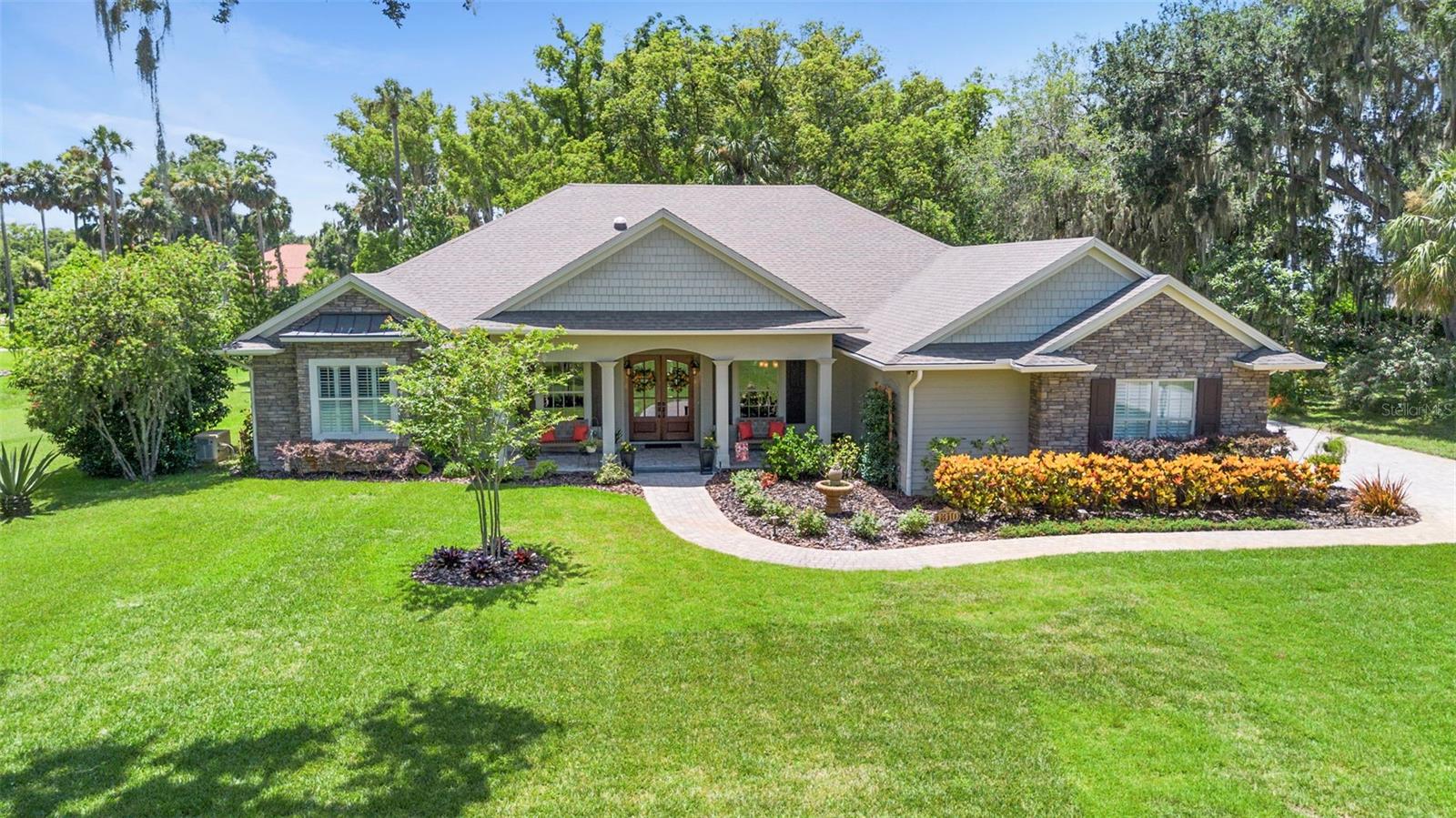 Custom Built Home on 1.3 Acres in Elysium, Mount Dora's Premiere Neighborhood. Welcome to 1310 Natureland Ct. Nestled on a beautifully landscaped 1.3 acre corner lot in a cul-de-sac of multi-million dollar homes. This neighborhood and home is adjacent to the beautiful Lake Dora and just minutes to Historic Downtown and all the Restaurants, shops, and the community events that make this town so special. Crafted by the esteemed local builder Sam Sadler, this residence blends timeless quality with thoughtful design. The open and functional floor plan features 3 spacious bedrooms, plus a den, ideal for an office or flex space. A formal dining area pairs beautifully with the kitchen nook for ample seating, offering multiple options for everyday living and entertaining. Enjoy the serene view through the aquarium glass into the lush back yard. Interior highlights, crown molding,Bermuda Shutters, built- in features, hardwood floors, tile in the wet areas and carpet in the bedrooms, all reflecting the appointments you would expect in a high-end home. The large kitchen provides the chef plenty of space, an island with a prep sink, and quality appliances to make cooking a joy. Enjoy Florida living at it's finest on the expansive rear lanai overlooking a serene professionally landscaped backyard with low voltage lighting for those romantic evenings. Built with durability in mind, with Hardie concrete composite siding and stone veneer. The oversized 3 car garage provides ample space for vehicles, tools, and a workshop. Best of all, there are no HOA fees, yet the deed restriction ensures compliance with property maintenance and aesthetics to protect your investment in a pristine upscale neighborhood. FULL HOUSE GENERATOR will be quite helpful, 2 Tank-less Hot Water Heaters powered by propane for utility efficiency. Don't miss your chance to own this exceptional home in one of Mount Dora's most sought after areas. Schedule your private showing today! Classy and Comfortable....make it yours today! Property is under audio and video surveillance.