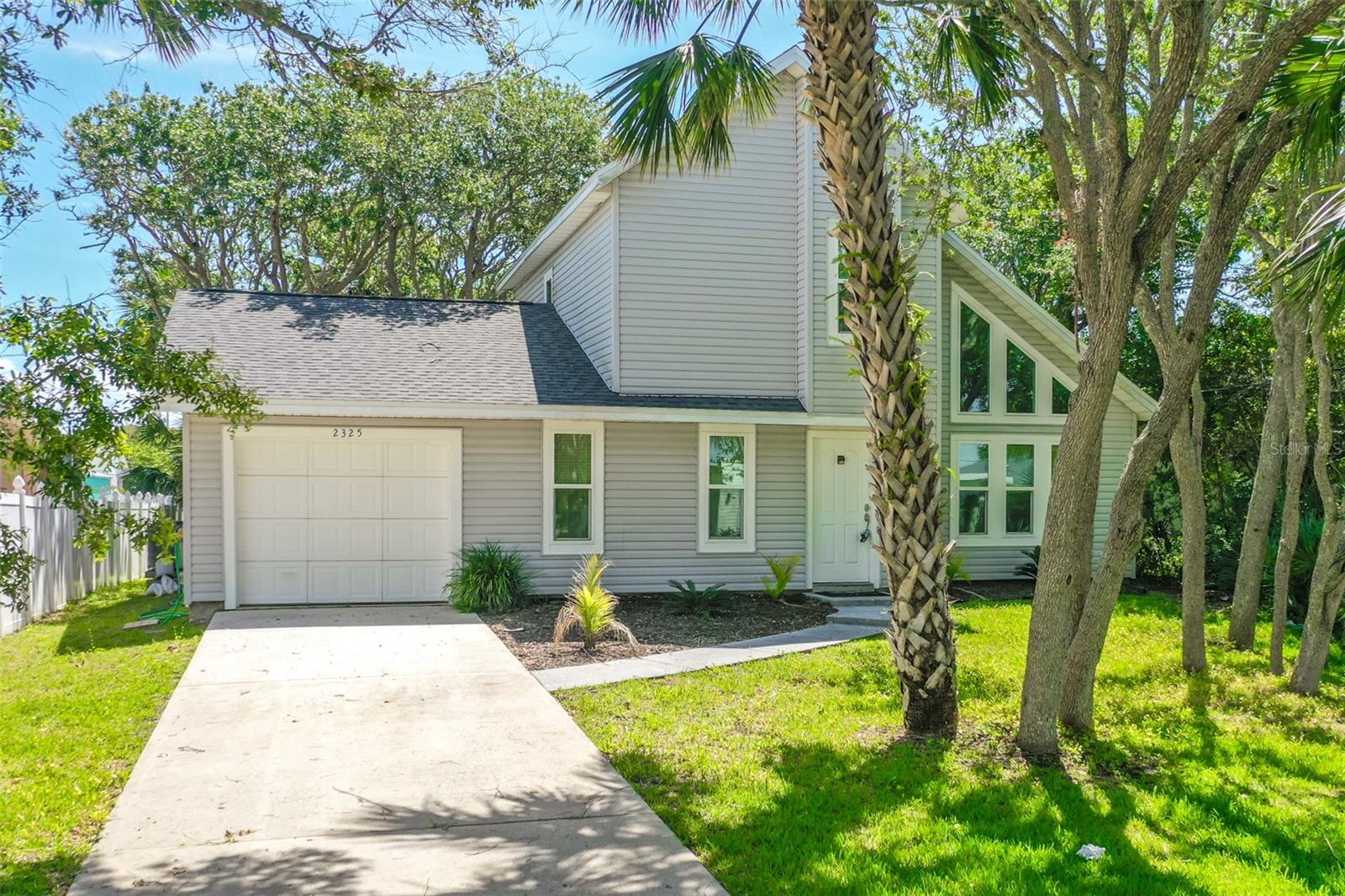 Situated on a peaceful street just 2.5 blocks from the shimmering sands of South Flagler Beach. Enveloped by the shade of grand live oaks and PALM TREES, this residence presents an ideal combination of coastal allure and contemporary ease. Inside, you'll discover vinyl and ceramic tile flooring throughout, enhanced by GRANITE countertops in both the kitchen and bathrooms. The property has been carefully updated with a NEW ROOF (2023), HVAC system (2018), hot water heater (2018), propane tanks (2020), IMPACT WINDOWS and SLIDING GLASS DOORS (2020), and a WHOLE HOUSE GENERAC generator (2019). The expansive living room on the first floor is bathed in natural light from strategically placed windows, fostering a bright and open ambiance. This level also features a bedroom with an ensuite bathroom that can be accessed from the hallway. The kitchen boasts sleek cabinetry and provides direct access to both the garage and the OUTDOOR LANAI. Upstairs, a flexible LOFT AREA with a closet, an extra bedroom, and a bathroom offers options for a home office or guest space. The backyard serves as a tranquil escape, with lovely palms and live oaks contributing to a serene atmosphere, along with a concrete platform ready for your ideal fire pit, hot tub, grill station, or any outdoor project you dream of. With all major systems recently updated, this home ensures peace of mind and a low-maintenance lifestyle. Seize the opportunity to reside in one of Flagler Beach's most desirable areas—where coastal living harmonizes with comfort and convenience.