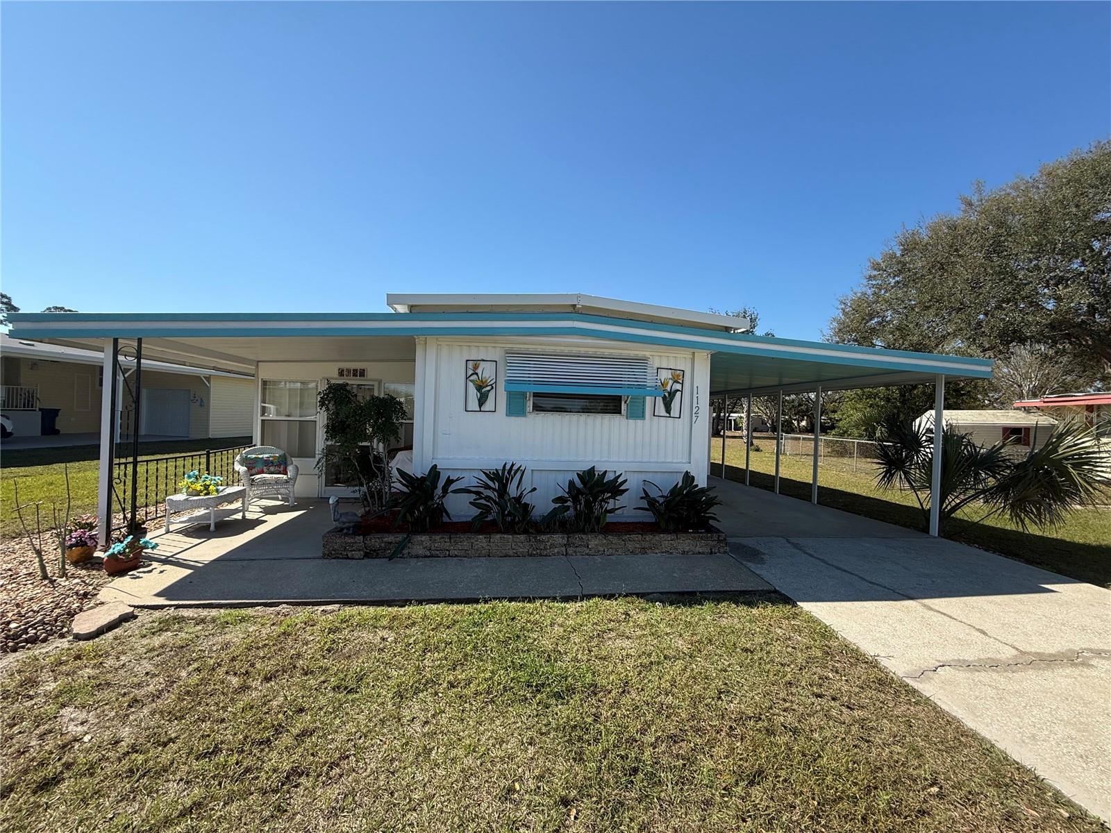 This sweet turnkey home is the epitome of Florida living. It is centrally located, as exciting Mount Dora is only 6 miles away and Leesburg is 5. Quaint Eustis is also 5 miles away. Grocery stores and drug stores are right up the street, along with Waterman hospital, and doctor offices. Feeling good in the neighborhood is an understatement with a large lot that is real estate. This 55+ community has it all! The club house with an impressive library and large activity hall which leads to an indoor heated pool and an outdoor pool as well, with more lounge chairs than a small cruise ship. This all over looks a lake with a walk out dock, to fish or simply bird watch. Making this a resort feel style of living. The home itself has new sub flooring throughout and laminate flooring. The roof is in good condition. The kitchen has new appliances, and the open floor plan allows for great conversations. The Florida room allows enjoyment no matter what the weather is. The front and carport patios allow choices for outside relaxing. There is a storage unit under the carport which holds the washer and dryer. The carport holds two vehicles as well. The large lot offers entertainment for family and pets.
