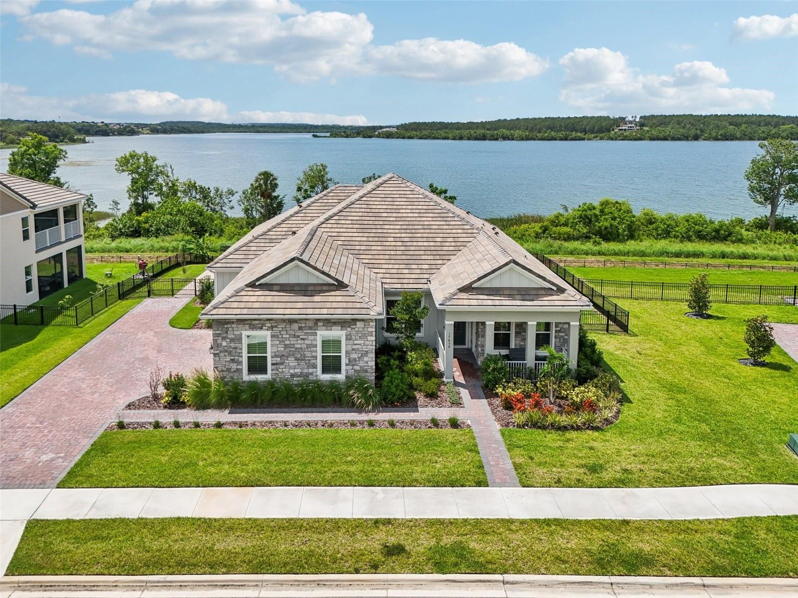 Enjoy lakeside living at its finest in this beautifully designed 4-bedroom, 3-bathroom home in Lake Apopka Sound, offering nearly 3,000 square feet of thoughtfully crafted space. From the moment you step inside, you’re welcomed by serene lake views and a wide-open floor plan that seamlessly connects the kitchen, dining, and living areas—perfect for entertaining or everyday life. Tray ceilings and upgraded tile flooring run throughout the main living spaces, while built-in shelving, a custom feature wall, and an electric fireplace add warmth and style. The kitchen is a true showpiece, featuring stainless steel appliances, a walk-in pantry, large center island, and breakfast bar. It opens to a spacious family room ideal for gathering and relaxing. The primary suite is a calming lakefront retreat with a spa-inspired bathroom that includes dual vanities, a soaking tub, and a separate walk-in shower. Electric window shades and plantation shutters are installed throughout the home, blending comfort and privacy. A standout feature is the attached in-law suite—a private 3-room space with its own exterior entrance, kitchenette, bedroom, and full bathroom—offering a flexible option for guests, multigenerational living, or a home office. Step outside to your fenced backyard and enjoy breathtaking views of Lake Apopka from the paver patio, complete with a motorized screen enclosure. The professionally landscaped yard is made for outdoor living, and additional upgrades include a whole-house Brita water softener system for clean water throughout and gutters for improved drainage. A spacious 3-car garage provides ample parking and storage. Just minutes from downtown Winter Garden and the lively Plant Street district, you’ll enjoy easy access to shops, restaurants, farmer’s markets, breweries, and community events. The West Orange Trail is nearby, offering miles of scenic biking, running, and walking paths. You’re also a short drive from brand-new shopping and dining in nearby Clermont, including Costco and other national retailers. With top hospitals, world-class theme parks, and downtown Orlando within reach, this home checks every box for comfort, convenience, and style.