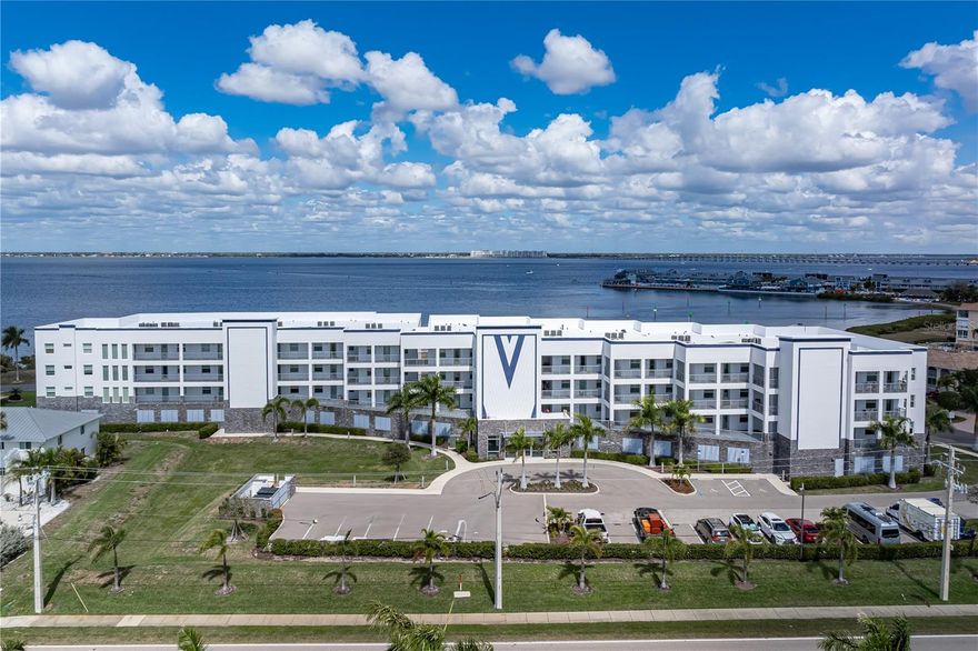 PARADISE POINTE CONDO W/UNOBSTRUCTED CHARLOTTE HARBOR VIEWS! The property checks all of the boxes - Newer, Big Water View and walking distance to downtown, Fishermen's, Village, Gilchrist Park and Yacht Club. Condo is furnished and offers private view that does not overlook the pool. It is the ideal 2 bed/2.5 bath residence at Paradise Pointe in Punta Gorda Isles. The private balcony captures wide-open harbor views with Fishermen’s Village and Sunseeker Resort visible across the water, where passing boats, evening sunsets, and the occasional dolphin sighting become part of daily life. Located just minutes from historic downtown Punta Gorda & walking distance to Fishermen's Village, the setting places shopping, dining, parks, and miles of Harborwalk trails close to home. Inside, the open-concept design seamlessly connects the great room, dining area, and kitchen, creating a spacious environment ideal for everyday living and entertaining. Architectural details include a striking coffered ceiling in the great room, recessed LED lighting, and large-format tile flooring throughout. Fresh interior paint enhances the light, coastal palette while impact-rated sliding glass doors open fully to the balcony, blending indoor and outdoor living. The gourmet kitchen is designed to impress with quartz countertops, stainless steel appliances, a beveled glass subway tile backsplash, and an oversized island with breakfast bar seating. White shaker-style cabinetry with contemporary hardware, crown molding and a built-in wine rack provides both style and storage. The spacious master suite offers a private retreat with a spa-like bath featuring dual vanities, a corner soaking tub, glass-enclosed walk-in shower, private water closet, and linen storage. The guest bedroom includes its own en-suite bath, creating comfortable accommodations for visitors, while a convenient half bath serves the main living area. Both bedrooms feature large, walk-in closets. Step outside to the balcony where side privacy walls create a more intimate outdoor setting while still capturing expansive harbor views. It’s the perfect place to start the day with coffee or unwind in the evening as boats glide across the water. Paradise Pointe is a luxury waterfront condominium built in 2020 with impact-resistant windows and doors and a new roof installed early 2026. Residents enjoy resort-style amenities including a harbor front pool and spa, grilling area with shaded gazebo dining space, secure lobby entry, elevator access, under-building assigned parking, and a private storage locker. From here, it’s an easy walk to Fishermen’s Village for harbor front dining, shopping, and entertainment, or to the nearby Isles Yacht Club for sunset dinners overlooking the marina. Waterfront parks, Harborwalk trails, marinas, shopping, and additional dining options are all close by, placing you in the heart of Punta Gorda’s active waterfront lifestyle. Move-in ready with most furnishings - see list of exclusions. Schedule your private showing today and start enjoying life on the harbor.