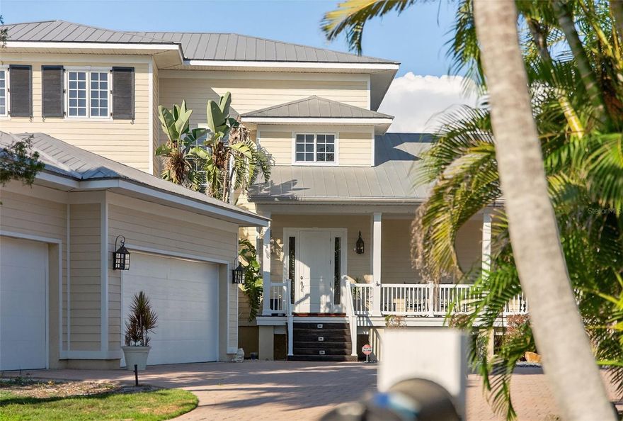 One or more photo(s) has been virtually staged. Exceptional Waterfront - North Siesta Key's Bay Island Boater's Dream - Exerience the best of coastal living in this elegant 4bd/4ba residence - just minutes to the Intracoastal Waterway. The home features a 2023 14,000lb dock/lift with electric and 3pnt moorage. Step inside a welcoming slate tile entry foyer to discover timeless quality design with Brazilian Ipe hardwood flooring throughout, hurricane rated windows and French doors and volume ceilings. At the heart of the home is a true cook's kitchen with Wolff Gas Range, built-in Sub-Zero stainless refrigerator, Fisher Paykel diswasher and soap-stone counter-tops. A true Chef's pantry, abundant cabinetry and full bar with wine refrigeration elevate the entertaining experience. The Primary Bedroom Suite, set in its own private wing, offers a tranquil retreat w/French Doors opening to a full private deck, perfect to enjoy sunrise and coffee; generous closet space and spa-inspired Bath; Guests Private wing and other rooms offer flexibility; French doors, automated window coverings, and architectural details create a refined and comfortable atmosphere. A full laundry room w/sink, office nook and mudroom are conveniently located off the 3-car garage.  Outdoors, enjoy multiple covered decks, one with gas-fireplace for perfect evening waterfront ambiance; overlooking heated salt-water pool/spa; lush tropical landscape; Minutes to downtown Sarasota.
