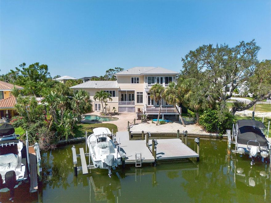 One or more photo(s) has been virtually staged. Exceptional Waterfront - North Siesta Key's Bay Island Boater's Dream - Exerience the best of coastal living in this elegant 4bd/4ba residence - just minutes to the Intracoastal Waterway. The home features a 2023 14,000lb dock/lift with electric and 3pnt moorage. Step inside a welcoming slate tile entry foyer to discover timeless quality design with Brazilian Ipe hardwood flooring throughout, hurricane rated windows and French doors and volume ceilings. At the heart of the home is a true cook's kitchen with Wolff Gas Range, built-in Sub-Zero stainless refrigerator, Fisher Paykel diswasher and soap-stone counter-tops. A true Chef's pantry, abundant cabinetry and full bar with wine refrigeration elevate the entertaining experience. The Primary Bedroom Suite, set in its own private wing, offers a tranquil retreat w/French Doors opening to a full private deck, perfect to enjoy sunrise and coffee; generous closet space and spa-inspired Bath; Guests Private wing and other rooms offer flexibility; French doors, automated window coverings, and architectural details create a refined and comfortable atmosphere. A full laundry room w/sink, office nook and mudroom are conveniently located off the 3-car garage.  Outdoors, enjoy multiple covered decks, one with gas-fireplace for perfect evening waterfront ambiance; overlooking heated salt-water pool/spa; lush tropical landscape; Minutes to downtown Sarasota.