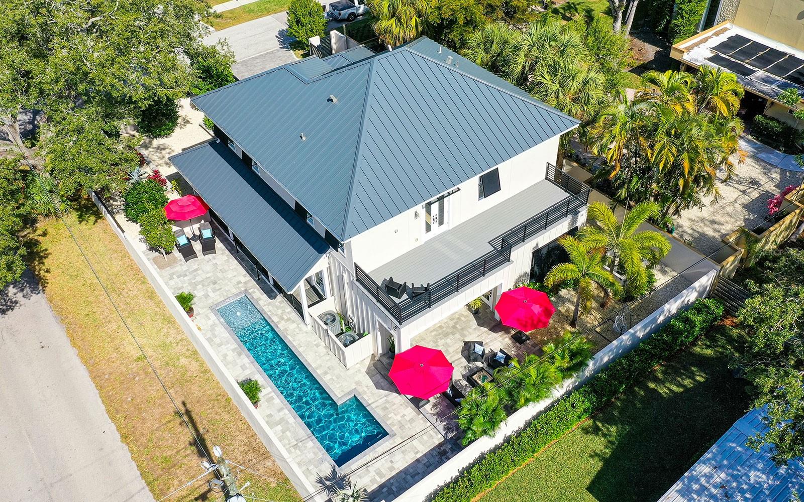 Nearly new custom home in Sarasota’s highly desirable Arlington Park. This 2021 residence strikes the perfect balance between classic design and contemporary living. Board-and-batten siding, standing-seam metal roof, vintage brick accent walls, authentic wood beams and shiplap accents are complemented by volume ceilings and top-of-the-line home components. The artful mix of colors, textures and patterns makes this neighborhood newcomer look like it has gracefully evolved over the years. Create a fabulous in-town oasis inside the flexible 3,153-square-foot floor plan ready to fit in with the way you live, congregate and entertain. At the heart of the home is an incredible high-end kitchen, anchored by a massive island surrounded by solid-wood cabinetry, quartz countertops, farmhouse sink and deluxe appliances including ILVE commercial-grade dual-fuel range, Viking chimney hood and full-size wine cooler. The island can also seat six for family meals and flows into the dining/family room which flows into the backyard pool area with wall-to-wall sliding glass doors. This home also nurtures the pleasures of me-time with a luxe owners’ suite where you can retreat and recharge, or quietly walk out a private door to the covered patio and pool area. The unique master bath features a dual vanity with trough sink, grooming station, free-standing bathtub and open walk-in shower. The rest of the bedrooms are upstairs along with a central bonus room and spacious 528-square-foot balcony. The backyard features a refreshing swimming pool with sun shelf, water fountain and colored LED lights, plus various sitting areas for lounging outdoors. The entire property is surrounded by easy-care landscape and privacy wall with automatic driveway gate and walk-in gate. A beautiful, old-growth oak tree anchors the corner of the property, perfectly positioned to provide natural cool shade over the home. Arlington Park is a friendly neighborhood, centrally located with super-easy access to downtown Sarasota, Sarasota Memorial Hospital, grade-A schools and an abundance of lifestyle amenities. This fabulous in-town oasis is ready to welcome you home!