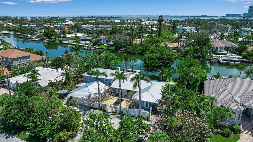 A Rare Coastal Offering – Half-Acre Canal-Front Lot Steps from Lido Beach and Minutes to St. Armands Circle. Opportunities like this are few and far between. Set on an expansive half-acre lot with 133 feet of wide canal frontage, this one-of-a-kind Florida coastal home invites you to embrace a lifestyle of relaxed elegance, natural beauty, and endless possibility. Just a short stroll from the white sands of Lido Beach and mere minutes to the shops and restaurants of iconic St. Armands Circle, this property blends location, charm, and potential in equal measure. Custom-built and brimming with architectural character, the home showcases timeless Florida design details, including pecky cypress paneling and accents throughout. A wood-burning fireplace anchors the spacious living area, creating a warm and inviting atmosphere. A true celebration of indoor-outdoor living, all four bedrooms offer direct access to the surrounding patios and garden spaces—blurring the line between interior comfort and natural serenity. The primary suite is conveniently located on the first floor, offering privacy and ease of living, while a separate guest apartment with its own private entrance makes an ideal in-law suite, guest quarters, or rental opportunity. Step outside to your private pool, set amidst lush tropical landscaping, and take in the peaceful water views. For boating enthusiasts, the property features a well-equipped dock already in place and ready for your boat—a rare amenity that offers immediate access to Sarasota’s sparkling waterways. The oversized lot offers plenty of room to create your dream outdoor living area, whether that includes a summer kitchen, firepit lounge, or garden oasis. While the home is structurally sound and filled with original charm, it’s ready for someone with vision to restore it to its former glory or reimagine it into a modern coastal masterpiece. This is not your typical cookie-cutter property—it’s a true original waiting to be transformed. Whether you’re seeking a personal retreat, a multi-generational escape, or an investment in one of Sarasota’s most desirable neighborhoods, this property offers the rare combination of land, location, and waterfront lifestyle.