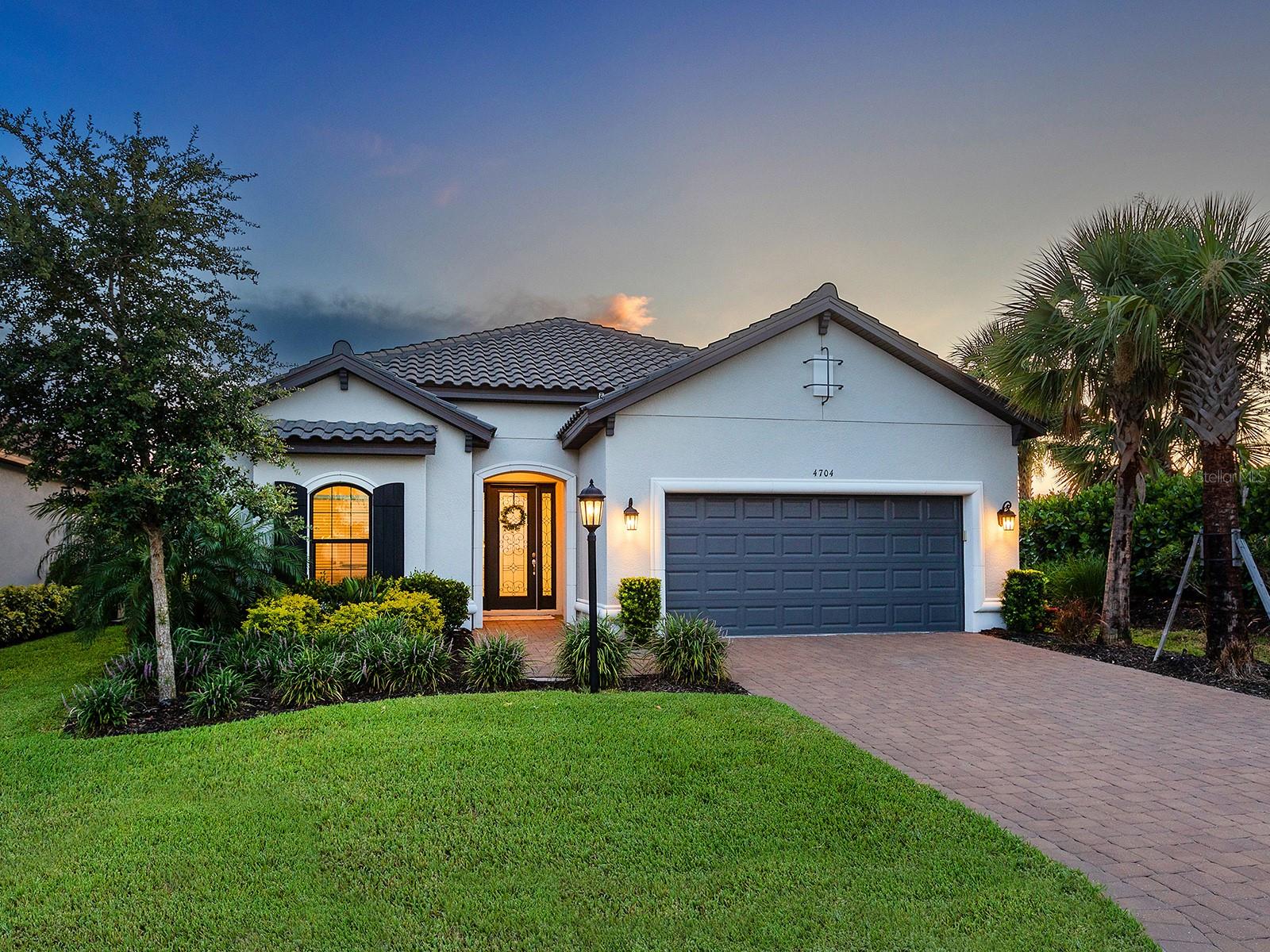 This GOLF DEEDED HOME has a full GOLF MEMBERSHIP INCLUDED! You will love this extended Lazio floor plan with upgraded lakeside living in amenity-rich Esplanade at Azario in Lakewood Ranch. With a spacious corner lot, extremely private landscaping, a desirable western exposure with picturesque sunsets over the lake every evening, and resort-style amenities at your fingertips, you will never want to leave this beautiful home. Recently constructed in 2022, this Taylor Morrison home offers exceptional upgrades beyond the builder basics in an extended floor plan with 2,375 SF of living space in an open and modern floor plan, and is also outfitted with impact windows and doors throughout. The interior boasts a modern and comforting ambiance with wood-look porcelain tile plank flooring, cool and inviting color palette, designer light fixtures, and wood and metal embellishments. The central entertaining area has a flexible great room and dining room space, ideal for family gatherings, entertaining, and daily living. The great room includes a custom shiplap feature wall, wood mantle, electric fireplace, contemporary ceiling fan, and impact sliding doors to the lanai. Chef’s will delight in the executive kitchen equipped with two-tone cabinetry with modern pulls, Quartz counters, farmhouse sink and prep sink both with brushed gold faucets, tile backsplash, walk-in pantry, and high-end stainless steel appliance suite. The kitchen space also features a custom-built wine bar with display cabinets and wine refrigerator. There is also enough space to add a bistro or café table with lake view for more dining and entertaining options. Additional impact sliders lead out to the paver lanai where a spacious covered entertaining space offers room for relaxing and dining next to the outdoor kitchen with stainless steel grill, separate burner, and bar fridge. The lap-style saltwater pool and spa has a waterfall feature and is gas heated so it can be enjoyed year-round. The immaculate details and comforting spaces continue into the primary suite with a feature wall of white shiplap and warm wood, geometric tray ceiling, and seating area overlooking the lake. The en-suite bathroom includes marble-look tile, a jetted soaking tub, walk-in shower with multiple shower heads and bench, dual sinks on a long vanity, and walk-in closet. Guests will enjoy two spacious guest bedrooms, one of which has an en-suite bathroom. Complementing the other fine features, you’ll find a private study with double pocketing doors, functional laundry room, and 2-car garage. Located just a 5-minute walk from the second amenity center, you are steps away from a lakeside resort-style pool, dog park, clubhouse, and community garden. The main amenities campus is just over 1 mile away featuring the main clubhouse, 18-hole golf course, restaurants, resort-style pool with Bahama Bar, tennis and pickleball courts, aqua driving range, golf pro shop, wellness center with spa service, robust calendar of social events and more. Lakewood Ranch is the top multi-generational community in the country for seven years in a row with plentiful shopping, dining, A-rated schools, parks, and nearby beaches