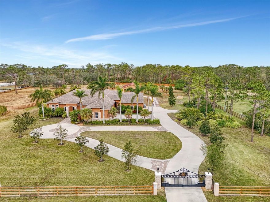 PROPERTY, PRIVACY, PANACHE– One-of-a-Kind Estate in Panther Ridge’s Premier Community Welcome to a stunning, hurricane-proof haven where luxury, safety, and sophistication meet. Nestled in the coveted community of Panther Ridge – The Pointe, this sprawling 6-acre estate offers unparalleled privacy and exceptional craftsmanship. A property designed for those who demand only the best, with features tailored for car enthusiasts, horse lovers, and anyone who appreciates the finer things in life. Your peace of mind is guaranteed with top-of-the-line safety features, including a 48kW whole-home Generac generator, hurricane-proof windows and sliders, remote-controlled hurricane shutters, lightning protection, and a built-in security system. IMPRESSIVE ENTRANCE & LAYOUT: A custom double entry gate with lighted stone columns opens onto a winding concrete driveway and a circular drive, welcoming you to the grand 4,551 sq.ft. home. Inside, a soaring foyer with imported Flos Italian glass chandeliers sets the tone for the luxury that unfolds throughout the residence. Polished matte travertine floors lead you to four expansive en-suite bedrooms, two elegant powder rooms, and a dedicated wine room showcasing a contemporary Italian light fixture, custom-built solid wood cabinetry, and wine refrigeration. The gourmet kitchen is a chef’s dream with Viking refrigeration, a Dacor gas cooktop, Miele built-in wall oven, and microwave, solid wood cabinetry, and stone countertops. Foscarini Italian pendants provide the finishing touch. The spacious family gathering area features a striking vertical gas fireplace with a custom Cambria Quartz backdrop and a built-in Italian wall unit. This home is ideal for entertaining or relaxing. Whole-house Niles audio, smart lighting, and energy-efficient fans ensure convenience and comfort throughout. The primary wing is a true retreat, with his-and-her walk-in closets, French doors opening to the pool area, and automatic shades. The grand primary bath offers dual stone vanities, separate garden tub, and a walk-in shower, all bathed in natural light. Spacious private guest suites on the first and second floors add flexibility and luxury. OUTDOOR OASIS & ENTERTAINMENT: Step outside to your resort-style saltwater pool and spa, surrounded by professional landscaping and new travertine pool deck. Relax in the covered outdoor kitchen veranda, complete with heaters and a Lynx commercial grill and bar...the perfect space for sunset cocktails or alfresco dining. For the car aficionado, the estate includes a 3-car attached garage and a 3+ car detached air-conditioned garage with high ceilings, epoxy floors, and a 7,500 lb. Bend-Pak vehicle lift. Horse lovers will appreciate the 2,400 sq.ft. barn featuring five box stalls, feed and tack rooms, a kitchen, bathroom, and even a washer/dryer. Additional wash areas, turn-outs, and paddocks with 4-rail wood fencing, make this the ultimate equestrian setup. UNBEATABLE LOCATION: Perfectly located just 5 minutes from Lakewood Ranch (#1 master-planned community in the U.S.), with the new Soleta Country Club and Terra Nova Equestrian Community nearby. Enjoy convenient access to shopping, restaurants, beaches, hospitals, and airports. The community itself offers miles of private wooded trails for biking, riding, and walking – an outdoor enthusiast’s dream. This exceptional property is barely lived in and offers a truly one-of-a-kind home in an idyllic location.
