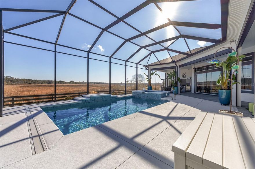 Welcome to an exceptional GRANDVIEW PREMIER HOME, Located in THE PRESERVE AT PINE HILLS, offering serene PRESERVE AND WATER VIEWS with luxurious indoor-outdoor living in a coveted setting. This meticulously maintained SALTWATER POOL/SPA home boasts a stunning outdoor kitchen, perfect for entertaining, and a beautifully landscaped exterior with a WATERFALL WALL and a grand paver CIRCULAR DRIVEWAY enhanced by elegant lighting. Step through the modern double-door entry to discover elevated design elements, including exquisite WATERPROOF LAMINATE FLOORING, soaring 12- to 14-foot ceilings, and stylish chandeliers that set a welcoming ambiance throughout. The open-concept living areas flow seamlessly from the inviting foyer to the formal dining, living room/library, and a chef’s dream kitchen. Here, you’ll find premium QUARTZ counters, high-end stainless appliances, soft-close cabinetry, and thoughtful details like a butler’s pantry and breakfast nook with custom built-in bench seating.
Retreat to the tranquil primary suite featuring custom storage, dual walk-in closets, and spa-inspired bath amenities including a Roman walk-in shower and split vanities. Three additional bedrooms provide versatile spaces for guests, home office, or hobbies. The family room’s massive stackable glass sliders open to the expansive screened pool cage, where you can enjoy the heated saltwater pool, spa, and breathtaking preserve and water views year-round.
This home is equipped for modern living with a full THREE CAR GARAGE, epoxy floors, mini split HVAC, EV and RV outlets, whole-house surge protection, and a Generac generator. Additional enhancements include hurricane screens for peace of mind, concrete block construction, advanced insulation, and a Pegasus whole-house water filtration system. Dual-zone HVAC, two water heaters, and a 2019 roof ensure both comfort and efficiency.
Located on a desirable northwest-facing lot, the exterior features lovely landscape beds, planters, and a covered front porch welcome you and your guests. Enjoy effortless Florida living with every amenity at your fingertips, in a home that combines timeless elegance with essential modern comforts. Watch our Beautiful Video Attached!