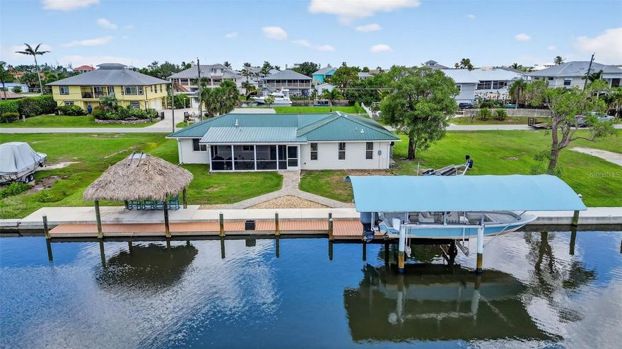 Waterfront living at it's finest!!! Welcome to the quaint community of Pirate Harbor! Hop into the boat from your backyard with your own personal boat lift, which offers direct and quick access to Charlotte Harbor and Boca Grande inlet with no fixed bridges. The open waters of Charlotte Harbor are a few minutes from your dock, where you can head off to fish, dock at local restaurants for a meal, or venture further out for beachcombing. Charlotte Harbor is one of the best sports fishing spots in the US. Snook, redfish and trout fishing from the end of your canal for miles in every direction. 12 miles by boat to world class tarpon fishing at Boca Grande Pass and the Gulf beaches of Sanibel, Captiva, Cayo Costa and Gasparilla Islands. This waterfront 3/2 home is move-in ready, and totally renovated from top to bottom. Beautiful luxury vinyl plank floors throughout, brand new white shaker-style cabinetry, Silestone countertops, recessed lighting, brand new bathrooms, barn door in master bath, new seawall in 2018, new roof in 2022, new AC in 2024, new windows throughout in 2015, brand new steel cables on 10,000+ lb. boat lift, fish cleaning station, and hurricane panels for all windows.There is an abundance of parking and space for boat trailer parking, and 100 feet of saltwater canal frontage with direct access to endless waterways. The home has lots of windows offering natural light, and water views from most of the house. Enjoy the outdoors from the large, tiled screened porch, as well as the Chickee hut (made by Miccosukee Native Americans) on the dock. This area is great for enjoying the most beautiful sunsets, entertaining, relaxing, fishing, etc. If you're looking for a well-maintained, move-in ready, million dollar waterfront view/access look no further! This should be a must-see on your list!