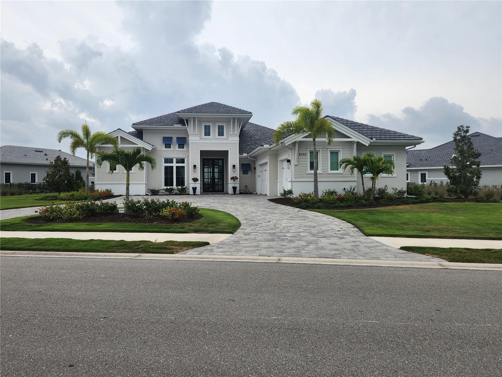 Welcome to your dream home! This stunning Gardenia III model by Stock Homes, built in 2023, offers unparalleled luxury with breathtaking water views from the moment you enter. Located in the distinguished community of The Lake Club, this property epitomizes cosmopolitan living with every detail meticulously designed.
The home boasts high ceilings and tile flooring throughout, creating an expansive and elegant atmosphere. The state-of-the-art kitchen features a large island, upgraded cabinets, and exquisite quartz countertops, with a convenient coffee bar off the kitchen adding a touch of daily luxury. Sliding pocket doors span across the back of the home, blending indoor comfort with outdoor serenity.
The tranquil and spacious primary suite includes a cozy sitting room, while the luxurious primary bathroom offers a sunken walk-in shower with multiple shower heads for a spa-like experience. All guest bedrooms are en suites, providing comfort and privacy for family and visitors, and a dedicated office caters to your work-from-home needs. A separate cassita offers additional space, perfect for guests or as a private retreat.
Enjoy the oversized saltwater pool with an integrated spa, ideal for relaxation and entertainment. Electric fireplaces indoors and outdoors create a cozy ambiance throughout the year. The outdoor kitchen is equipped with high-end appliances, including a large free-standing pizza oven, perfect for alfresco dining. Hurricane impact glass throughout the home and drop-down hurricane screens enclose the entire outdoor pool area, providing safety and peace of mind.
Additional features
include a three-car garage, offering ample space for vehicles and storage. The great room features an electric fireplace, built-in pre-lit shelves, and a coffered ceiling for an added touch of elegance. This luxury home combines modern amenities with timeless design, ensuring a comfortable and stylish living experience. Don't miss the opportunity to own this masterpiece in The Lake Club, where luxury meets tranquility.
There is a one time $2500 contribution to the HOA at the time of closing. There is a $1200 a year dinig expense.
