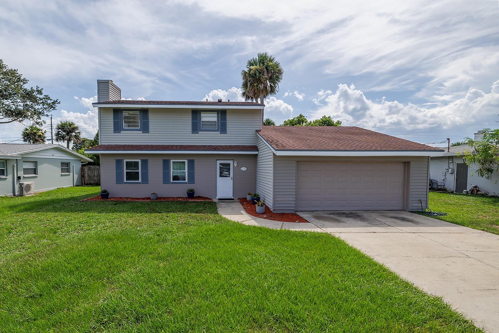 Ever dreamed of having two master suites or the perfect in-law setup? This spacious and freshly painted 4-bedroom, 3-bathroom home offers a rare layout with a private en suite bedroom on both the first and second floors. Enjoy classic terrazzo floors, a cozy fireplace, and a large downstairs master suite, plus a beautifully updated kitchen featuring quartzite countertops, soft-close cabinets, a deep chef’s sink, coffee station, stylish fixtures, and 2023 stainless steel appliances. The open-concept design includes indoor laundry with sink and a generous yard with no HOA. Upstairs showcases gorgeous wood floors, two large guest rooms, a full bath, and a huge second master with en suite bath and walk-in closet. Car lovers will appreciate the oversized two-car garage with vaulted ceilings for a lift, workbench, drink fridge, and tons of storage. Recent updates include a 2025 water heater and 2023 HVAC. Located just steps from grocery and department stores, and minutes to the beach and only 1.5 hours to Orlando—this home has it all!