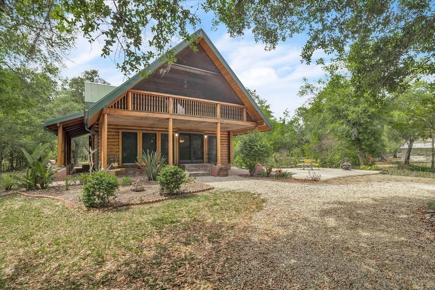 Tucked away on this beautiful wooded five acres, is a two-story 3 bedroom 2 full bath A-frame log cabin that offers a rare blend of rustic charm and refined finishes. Paired with an expansive 4,210 square foot barn that can be used for car enthusiasts or can be easily turned back to horse paddock, with additional outbuildings for ultimate versatility. Built in 2008, the home features an open-concept first floor where the living, dining, and kitchen areas flow seamlessly, showcasing true log-cabin craftsmanship. Exposed wood beams, soaring ceilings, natural wood flooring, and expansive windows fill the interior w abundant natural light, creating a cozy yet airy ambiance. The kitchen is a chef’s dream, with custom wood cabinetry, elegant marble countertops, decorative tile backsplash, a gas cooktop, built-in convection oven, and a center island with bar seating—perfect for entertaining. The main level also offers 2 nice sized guest bedrooms with built-in closets, a custom full bathroom with a walk-in shower and marble-top vanity, and a conveniently located laundry room. Upstairs, a spacious loft-style family room opens to a charming screened front balcony overlooking the expansive front yard. The primary suite features a cedar walk-in closet, a private balcony with views of the backyard and natural landscape, and an updated spa-like bathroom with natural wood ceilings, exposed beams, a custom double vanity, and a large glass-enclosed walk-in shower with floor-to-ceiling tile and abundant natural light. Downstairs French doors open to the outdoor front patio, ideal for enjoying the peaceful, private surroundings. Directly outside is a large open patio for entertaining right next to a beautiful winding creek that leads to a stocked pond. Adding to the property’s appeal, the 4,210 square-foot barn includes a small apartment w/full bath and multiple versatile rooms, while a detached building provides additional space for equipment.  A gated front driveway first leads to the barn before reaching the home, offering exceptional privacy. This property perfectly blends the warmth and character of a log cabin with versatile outbuildings; Totally Fenced five acres. Nestled in Arcadia, it offers an ideal balance of privacy and convenience. Zoned A-10, the property provides the perfect setting to bring horses, raise livestock, or create your own hobby farm, with ample space for barns, paddocks, and outdoor activities. Just minutes from downtown Arcadia, you’ll enjoy easy access to grocery shopping at Publix and Walmart, local favorites like Slim’s Bar-B-Q and Brother’s Fish House, and a variety of casual dining options. Families will appreciate nearby West Elementary, DeSoto Middle, and DeSoto County High School, while outdoor enthusiasts can explore Morgan Park, the Peace River, and local trails for boating, fishing, and picnicking. Craft your gorgeous private retreat and enjoy the freedom and flexibility this home allows.  **PLEASE ENJOY THE 3D INTERACTIVE VIRTUAL TOUR ASSOCIATED WITH THIS LISTING**