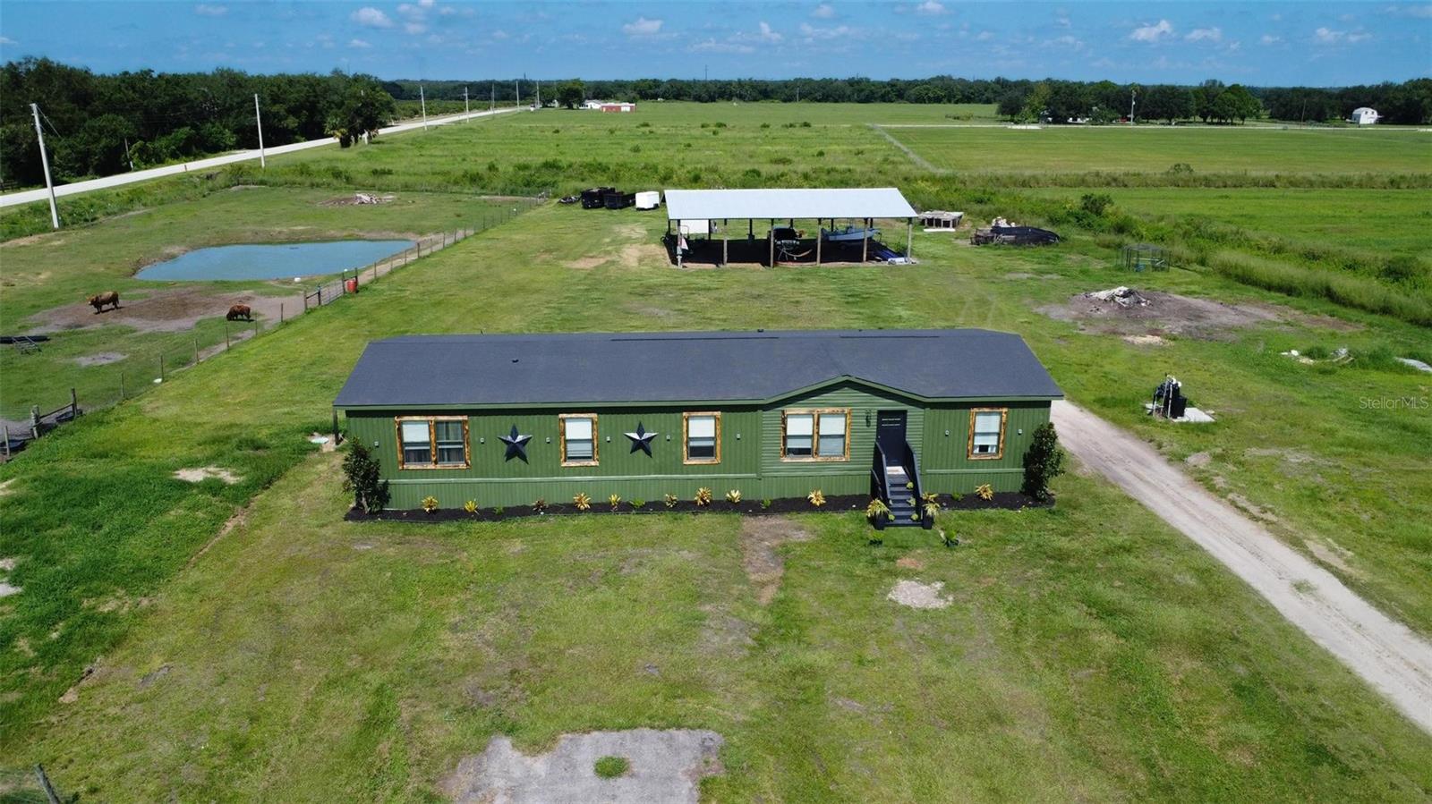Welcome to 4951 SE Airport Road! Discover the perfect blend of modern comfort and rural charm with this beautifully updated 2023 manufactured farmhouse situated on a fully fenced 5.9-acre spread in desirable DeSoto County, Florida. Step inside to find a fresh, stylish interior featuring updated and customized finishes, a spacious open floor plan, and modern farmhouse touches throughout. The light and bright living area has a seamless flow from living and dining into the chef’s kitchen and additional family room. The kitchen boasts a large island with seating, stainless steel appliances, and plenty of space for entertaining and family meals. The primary suite is a private retreat with a luxurious en-suite bathroom featuring a large walk-in closet and complete with double vanities, and walk-in shower. Three additional bedrooms and the second full size bathroom can be found on the opposite side of the home to provide the desirable split bedroom design. Each of the bedrooms are of a generous size and provide plenty of room for multiple furniture sets and styles. Outside, the property is thoughtfully set up for agricultural use or recreational enjoyment. It includes a large pole barn with RV hookup, fenced pastures ready for all types of livestock one paddock supports a pond for livestock, irrigation or relaxation. The home has also just had an extensive revamp featuring brand new siding, skirting, paint, woodwork, floors and water softener system. This home is ideal for those seeking a large home with hobby farm just bring your livestock and enjoy country living at its best because this is the Florida countryside lifestyle you’ve been looking for. Schedule your private showing today and come experience the freedom and beauty of rural DeSoto County!