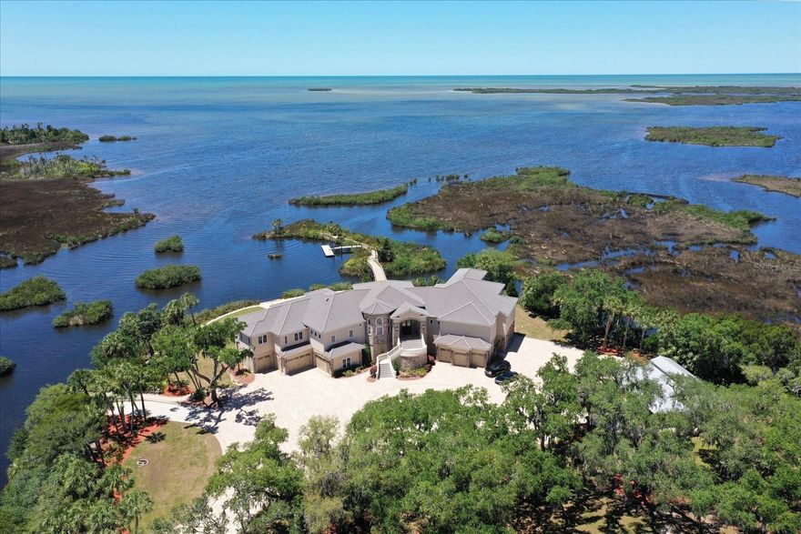 BUILT TO WITHSTAND A CAT 5 HURRICANE, LIVING SPACE OF THE HOME COMPLETELY UNTOUCHED BY HURRICANE HELENE! Some repairs being made to outbuildings and garage doors below the home.  MOVE IN READY!  TROPICAL GULF OF MEXICO LUXURY ESTATE – This stunning Gulf front property, comprised of over 23 acres, with over 1,100 feet of waterfront on the Gulf of Mexico, with incredible water views from every room is a one-of-a-kind opportunity. The residence is comprised of 5 bedrooms and 5/2 bathrooms in over 8,950 sq ft of living area.  Bathed in sunlight, the split plan residence comprises a large entrance hall, living room, generous dining room, butler’s pantry, gourmet kitchen, 350-bottle wine cellar, large walk-in pantry,  informal dining area,  family room, billiard room, library, professional built 28 seat home theatre, exquisite master suite, opulent en-suite, all showcasing breathtaking views of the Gulf of Mexico. Gated, safe & secure, with a generator that will run the entire home for a month. Outside, a magnificent west facing terrazzo terrace extends the entire length of the home, with an outdoor kitchen with breathtaking Gulf views.  Outdoor highlights also include a boat ramp, rustic boat house,  a historical rustic guest house, a bridge which leads to an island with a floating boat dock, and double (lighted) tennis courts all amid the beautiful coastal wilderness. A car collectors dream featuring a 40+ car garage, with height for car racks and 12 garage doors, including a utility door, for Helicopter or RV and spans the entire space under the home. The 30,000 sq. ft. motor court makes landing a helicopter easy!   The region is a prime spot for water sports and fishing. One of Florida’s most captivating Gulf Coast homes, this private, opulent home is cleverly designed to maximize its position overlooking the Gulf of Mexico.
