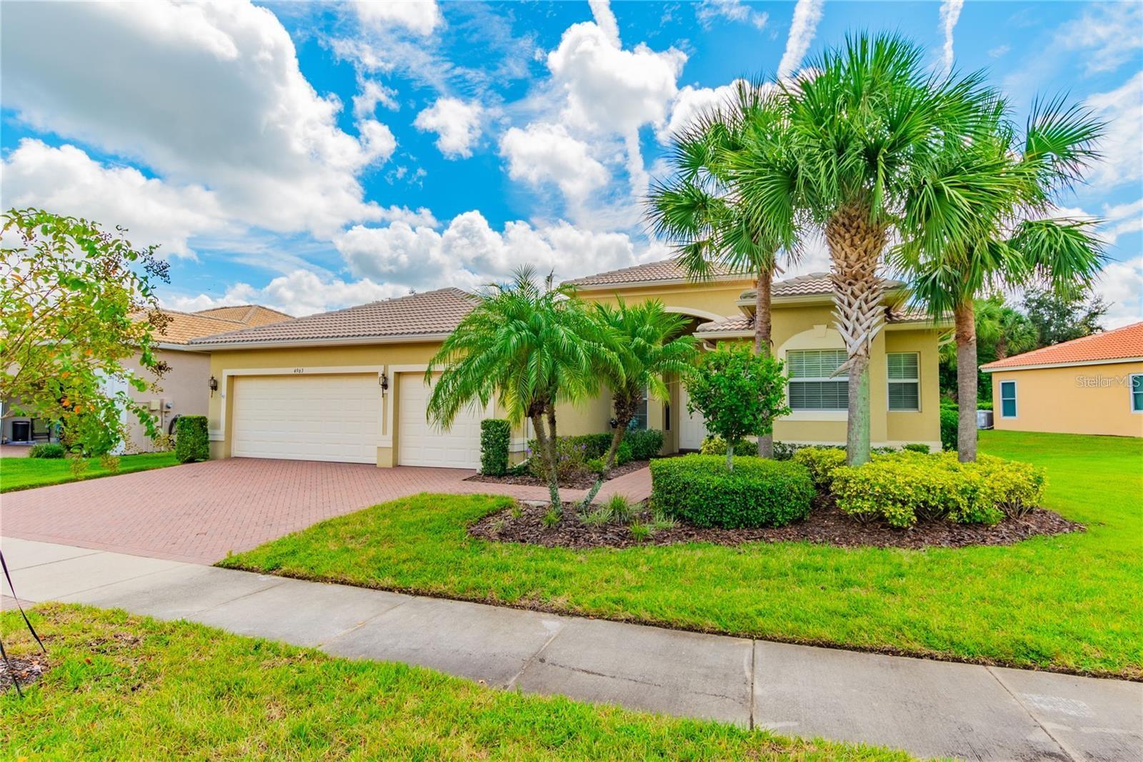 One or more photo(s) has been virtually staged. This bright and airy Rialto model is move-in ready and ideally situated on an oversized homesite in Valencia Lakes, Tampa Bay’s premier 55+ active community. Thoughtfully updated by the current homeowners, the residence showcases new luxury vinyl plank flooring in bedrooms, fresh interior paint, and refinished white-painted maple cabinets with updated hardware. A 2019 Carrier HVAC system with UV light adds to the comfort and efficiency of the home. From the moment you arrive, you'll notice the spacious 3-car garage, lush mature landscaping, and the extra space between homes that offers both privacy and a peaceful atmosphere. Inside, the well-designed Rialto floor plan features three spacious bedrooms, two full bathrooms, a half bath, and a three-car garage. The main living areas are finished with elegant 17x17 diagonal-set tile, with no carpet throughout the home. The formal dining room impresses with its coffered ceiling and crown molding, setting a sophisticated tone for entertaining. The great room, kitchen, and casual dining space flow seamlessly into one another and open to a generous 25 x 10 screened and covered lanai. This outdoor retreat overlooks lush landscaping and a tall berm that enhances the sense of backyard seclusion. The open-concept gourmet kitchen is a chef’s delight, featuring 42" white-painted maple cabinetry, brushed nickel hardware, built-in cabinet pantry, under/over-cabinet lighting, glass cabinet doors with downlighting, granite countertops, an extended serving bar with an 18" bar top, tumbled marble backsplash, and stainless steel appliances. The primary suite is a tranquil haven with a coffered ceiling, crown molding, luxury vinyl plank flooring, and dual walk-in closets. The primary bath is designed for comfort and style with dual vanities, Corian counters, and a spacious walk-in shower with built-in seat and ceiling-height tile. A split bedroom layout ensures privacy, with the secondary bedrooms located away from the master suite. The second full bath includes a tub/shower combo, white maple cabinetry, and Corian counters with a banjo top, while a convenient powder room with pedestal sink serves guests. A fully equipped laundry room offers a washer and dryer, upper cabinetry for storage, and a utility sink with built-in cabinetry. Additional features include a whole-house water softener system, 50-gallon water heater with thermal expansion tank, ceiling fans, upgraded light fixtures, crown molding throughout, rain gutters, epoxy-coated garage floor, and garage ceiling storage racks. Living in Valencia Lakes means enjoying a vibrant lifestyle with access to a 40,000 square foot clubhouse, resort-style pools, pickleball and tennis courts, a bistro, art and social clubs, fitness classes, a 24-hour gym, live shows, and so much more. This is resort-style living at its finest—don’t miss your opportunity to make this stunning home yours.