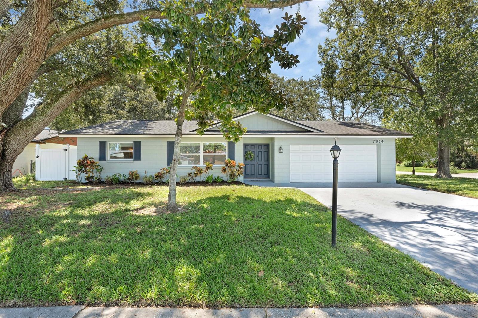 This beautifully updated 4 bedroom, 2 bathroom, 2 car garage home offers modern style, thoughtful upgrades, and a prime location just steps from the neighborhood elementary school. From the moment you arrive, you’ll notice the curb appeal of the corner lot framed by mature trees and a newer white vinyl fence. Inside, the home features a spacious split floor plan with wood-grain laminate flooring, recessed lighting, and UPDATED fixtures throughout. The custom kitchen is a chef’s dream with granite countertops, white cabinetry, a large island, stainless steel appliances, and a perfect sized pantry—seamlessly opening to the dining room AND great room for effortless entertaining. Retreat to the oversized owner’s suite with a SPA-LIKE private bath showcasing custom tile work, dual vanities, and a his-and-hers closet. Secondary bedrooms feature large closets and share a beautifully updated bathroom, as well. The home also offers formal living and dining spaces for flexible living. Step outside to enjoy a fully screened patio with stunning tile flooring—perfect for relaxing or hosting guests year-round. Peace of mind comes with a NEWER roof, NEWER A/C, and NEWER water heater, as well as updated double-paned WINDOWS, with beautiful wood blinds and elegant touches like 5 inch baseboards and serene colors throughout. The home comes complete with a functioning Rainbird irrigation system, as well. Don’t miss the chance to own this move-in ready home combining style, function, and comfort in one perfect package!