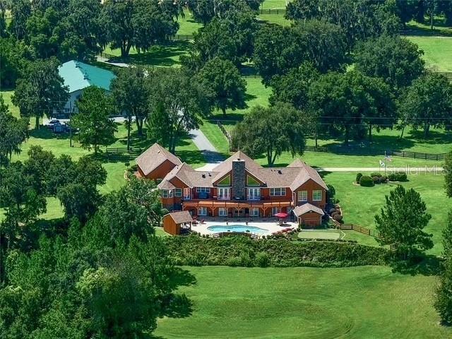 Welcome to Eagle’s Rest Equestrian Estate – A Premier Horse Country Retreat!
Nestled just 22 miles from the World Equestrian Center and the vibrant heart of Ocala, this exceptional estate offers the ultimate in equestrian living. Enter through a picturesque drive lined with grand oaks and classic 4-board fencing, and you’ll immediately sense the beauty and tranquility of this one-of-a-kind property.
As you approach the main residence, you’ll pass the impressive 35-stall barn—just one of the estate’s standout features. Inside the custom-built home, soaring pine ceilings, a dramatic 23-foot fireplace, and polished cherry wood floors set the stage for both elegant entertaining and relaxed country living. The spacious living area includes built-in entertainment, a wet bar, and a cozy loft, all framed by a wall of French doors offering stunning views of the aquifer-fed pond and gently rolling hills.
The gourmet kitchen is a chef’s dream with granite countertops, custom wood cabinetry, dual ovens, a large gas cooktop, and a convenient breakfast bar. Adjacent to the kitchen, a charming dinette and formal dining room both offer scenic views and artistic touches.
The owner’s suite is located in a private wing, featuring two walk-in closets, a luxurious en suite bath with dual vanities, jetted tub, and walk-in shower. A connected office/sitting room with panoramic windows leads to the upper deck and pool area. Also in this wing is a flexible bonus room ideal for a gym, studio, or additional bedroom.
The lower level offers two guest bedrooms with private baths, a game room, wet bar, and direct access to the pool, spa, and a pool house/studio. Outdoor living is just as impressive with an expansive upper deck, built-in grill, lanai with brick oven, cabana, and two spiral staircases for convenient access between levels.
In addition to the main home, the estate includes a spacious 2,340 sq ft guest house, two separate 2-bedroom apartments, two barns with a total of 43 stalls, 19 turnouts, four fenced pastures, and miles of paved driveways and fencing.
Recent upgrades include new asphalt roofs (2023) and state-of-the-art Trane 454B HVAC systems (March 2025), along with many more 2025 improvements too numerous to list.
Eagle’s Rest is a rare opportunity to own a turnkey equestrian estate in one of Florida’s most sought-after horse country locations. Schedule your private tour or request a detailed overview to explore everything this extraordinary property has to offer.