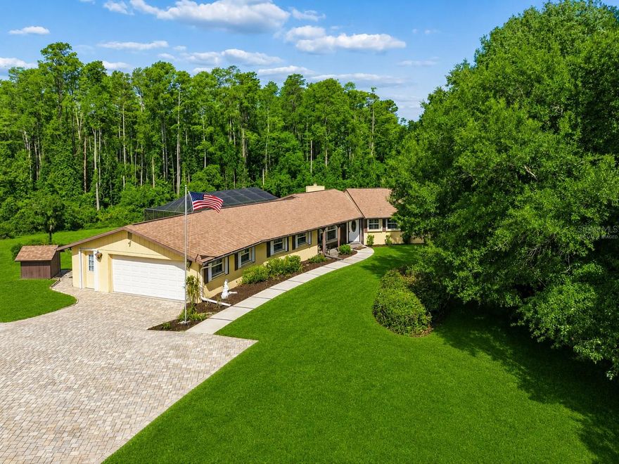 Set on 2.39 private acres in the highly desirable Tanglewood East community, this beautifully maintained 4 bedroom, 2.5 bath pool home offers the perfect blend of privacy, functionality, and peaceful Florida living. Positioned on an elevated homesite with a long paver driveway and surrounded by mature cypress trees, the property delivers a secluded setting while still being conveniently located near shopping, dining, and major roadways. Inside, the home features a spacious traditional layout with real wood flooring, tile throughout the main living areas, plantation shutters, newer windows, and hurricane shutters on all doors and windows. The inviting family room is centered around a wood-burning fireplace with stone accents and custom built-ins, while double French doors open to the private screened pool area with extensive paver decking, covered outdoor living space, upgraded screens, and a decorative fountain feature. The updated kitchen offers all-wood cabinetry, granite countertops, upgraded appliances, and a large eat-in dining space overlooking the beautifully private front yard. A spacious flex room with closet provides endless possibilities for a fourth bedroom, home office, media room, or additional living area. The oversized primary suite features double closets and an updated en-suite bath with upgraded stone and travertine finishes. Surrounded by mature landscaping, wooded privacy, and abundant wildlife, this property delivers the kind of acreage lifestyle buyers are actively searching for in one of the area’s most sought-after communities.
(ROOF-2020)(A/C #1-2026)(A/C #2-2020)(W/H-2006)(SEPTIC pumped & cleaned-12/2025)