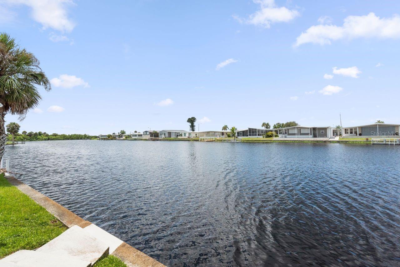 Enjoy everyday with the gentle shimmer of STUNNING CANAL FRONT WATER VIEWS from this RARE 3 BEDROOM, 2 bathroom retreat in Harbor Cove, an affordable 55+ waterfront community with GULF ACCESS. This spacious 1,341 sq. ft. FURNISHED home in the pet section invites you to unwind in a living room that opens to a wide canal, where manatees swim and herons perch just beyond your patio. The open kitchen and dining area offer generous counter space and cabinetry, perfect for preparing meals as sunlight filters through the skylights. A split bedroom plan ensures privacy in the large primary suite but also offers direct views through the living room access when desired. Two additional bedrooms near the hall bathroom make it easy for family and friends to be comfortable. Step outside and find your covered porch nearly at the water’s edge, perfect for gathering with friends for evening beverages, watching the boats go by or some backyard fishing. The HOA maintains the seawall and with a leasehold fee of just $99 PER YEAR, this is very affordable living in harmony with nature. Updates within the past 4 years include a new AC system, carport, siding, gutters, living room vinyl flooring, bathroom tile, renovated shower, and more. A long driveway, carport, and shed provide ample space for guests and gear. Beyond your doorstep is a 90-slip marina, amazing fishing and boating opportunities along the Myakka River, two swimming pools, a hot tub, bocce and shuffleboard courts and a 2-story clubhouse alive with dances, outdoor picnics, games, and community fun. Join the boat club or woodworking shop, participate in water aerobics and volleyball, craft classes, plays, etc. An optional fitness center, tennis/pickleball courts, boat slip and storage compound are also available. Located just minutes from beaches, restaurants, farmers markets, golf courses, spring training baseball, shopping and quality medical care this is one not to be missed! Schedule a private showing today.