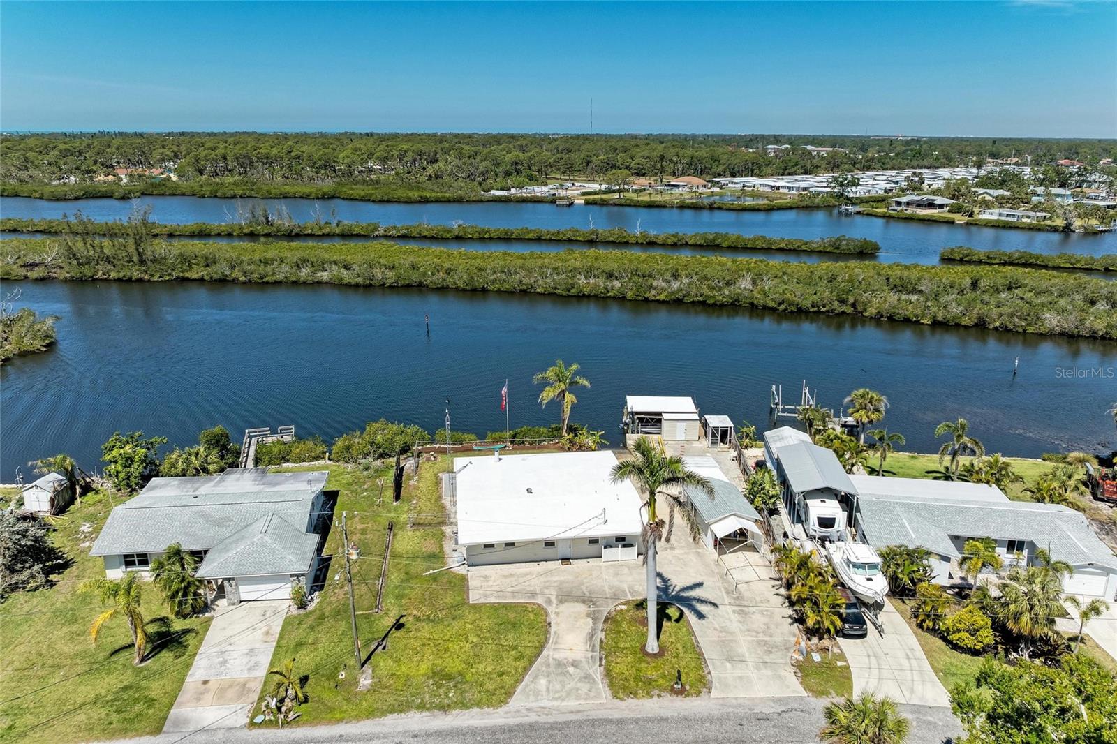 This waterfront home offers incredible potential, situated on a beautiful lot with desirable amenities and unique features. While the property experienced flooding, it is primed for renovation, providing a blank canvas for those seeking to restore or build their dream home.
Boating enthusiasts will appreciate the grandfathered boat ramp, covered boat lift, and a well-equipped dock complete with electric and water hookups, ideal for your watercraft and outdoor enjoyment. You can be to the Gulf in 20 minutes with bridges maintaining minimum height of 12FT. There is also a screened-in Fish cleaning/Cook room with electric and water. The riprap seawall ensures durability and protection along the water's edge. Additionally, there’s a spacious workshop with an overhead door, which could easily be converted back into a garage if needed and carport. Fantastic views and sunsets can be enjoyed in your backyard with patio, paver block firepit and banana trees and oyster plants. The home boasts 3 Bedrooms, 2 Baths and Mother-in-law suite with gas stove and sink. Large walk-in pantry off kitchen. At the rear of the home you have 2 sets of double pocket sliding doors. Home maintains Central Air and Heat, County water and septic. Home has also been replumbed and all cast iron pipes removed. There is also a sprinkler system and generator available to power the home in case of electrical outage. With ample space and unique features, this property provides the perfect opportunity to create a waterfront retreat with endless possibilities. Whether you’re looking for a place to live or a potential investment such as an Airbnb or VRBO this property will check all the boxes! Call today for your private showing.