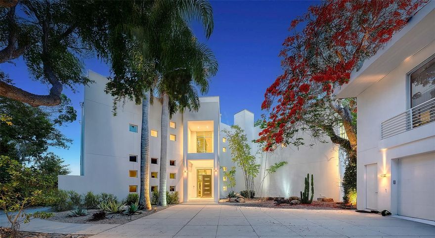 One or more photo(s) has been virtually staged. Celebrated as one of SRQ Magazine’s “Home of the Year” in 2008 and born from the visionary imagination of acclaimed architect Mark Sultana and built by Voigt Construction, this extraordinary waterfront estate is not simply a home — it is a lifestyle. One of Siesta Key’s most iconic private residences, it stands as a living testament to the art of inspired modern design and the art of living beautifully.

Deeply set on nearly one private acre along the tranquil Coconut Bayou, this gated 4-bedroom architectural masterpiece unfolds across multiple stories with absolute privacy, lush tropical splendor, and grounds generous enough for a pickleball court — all anchored by a fully separate guest house for family and friends who will never want to leave.

From the moment the gates open, life here feels different. A breathtaking composition of glass, steel, and sculptural lines soars beneath dramatic ceilings, with natural light pouring through at every angle — whether that’s a lazy Sunday morning or a dinner party in full swing. Rise by private elevator or ascend the sweeping steel-and-glass staircase to the crown jewel of this residence: a 2,500 sq. ft. rooftop terrace, where the Siesta Key lifestyle reaches its absolute peak. Panoramic views sweep across Siesta Key, the downtown Sarasota skyline, and the shimmering waterways below — this is where memories are made.

At the water’s edge, a brand-new dock on order, a double jet ski lift, and a dedicated kayak and paddleboard launch await — with direct, bridge-free access to the Intracoastal and the open Gulf beyond. This is the rare address that refuses to make you choose: the serenity of bayfront living, the thrill of open-water boating, and the privilege of private deeded beach access to the shores of Siesta Key — all from a single extraordinary estate.

Designed with both beauty and resilience in mind, the residence sits impressively high and dry above the Bayou. Even through recent storms, the property remained untouched by flooding — including the pool area — offering a rare sense of peace of mind along Sarasota’s waterfront.

The primary suite is a private world of its own — featuring a dedicated office/loft or exercise room, two custom walk-in closets, and a private balcony suspended above the Bayou. At the center of it all, an indulgent Champagne Jacuzzi infinity bathtub transforms every evening into a spa retreat. Downstairs, entertaining flows as naturally as conversation — from a dedicated movie theater room to tiered outdoor patios crowned by a spectacular summer kitchen, an open saltwater pool, and glowing fire bowl accents that keep the night alive.

In the kitchen, Italian custom cabinetry, top-tier appliances, a service pantry, and a private wine cellar come together in a space as pleasurable to cook in as it is to gather around. Garage parking for five vehicles and separate guest quarters complete an offering with virtually nothing left to wish for.

Minutes from The Out-of-Door Academy, Siesta Key Village, and Siesta Beach — this is not just an address. It is a life you’ll never want to leave.