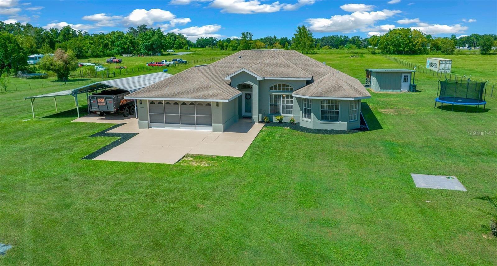 NEW ROOF 2025 . Great opportunity to buy This stunning Move-in ready 3-bedroom, 2-bathroom home is a true gem, boasting a screened-in pool with a new electric pump motor and light and offering 1,611 square feet of living space on a spacious 3.04-acre lot.As you step inside you'll be greeted by high ceilings and luxury vinyl plank (LVP) flooring throughout, creating a modern and stylish ambiance. Natural light floods the home, illuminating the open and spacious layout. The kitchen situated in the heart of the home, is perfect for entertaining and hosting family gatherings, making it a focal point of the property boasting Corian countertops and plenty of cabinet space. The master bedroom is a true retreat featuring a en-suite bathroom with a large tub, double vanities, tile walk-in shower and a door that leads out to the pool for added convenience. Split floor plan with two spacious guest bedrooms conveniently located near the guest bathroom. Out the back door is your own private screened in pool area, ready for family gatherings or pool parties. The home also includes a 2-car garage with ample storage space, tile flooring plus an additional kitchen area, as well as a 30x40 carport ideal for storing a boat or RV providing plenty of room for all your vehicles. The beauty of this property extends beyond the home itself, as the 3.04-acre lot is completely cleared and fully fenced with new front gate and electric motor , creating a perfect setting for horses, cows, goats or any other farm animals you desire. As an added bonus there is a 15x27 storage that was restore by the owners recently ,shed with electric that offers ample space for all your storage needs. But that’s not all—this shed also includes a 15x16 horse stall providing a secure space for your horses or livestock. Located minutes from stores, restaurants, hospitals and The Villages. For all the horse enthusiasts it’s located only 27 miles from the World Equestrian Center, Ocala & 11 miles from Florida Horse park. Don't miss the chance to own this stunning property and create your own mini-farm in this desirable location! NEW LVP FLOORING-2023 & SEPTIC TANK PUMPED OUT- 2024.