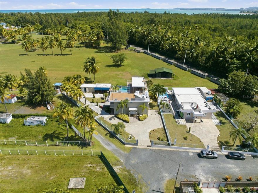 PALMA SOLA, Las Picuas, Rio Grande, Puerto Rico 5 Bedrooms · Ocean Front · Pool OFFERED AT: $2,400,000 Discover your Caribbean oasis in the quiet Las Picuas neighborhood, just five minutes from Rio Mar resort. Perfect for beach lovers, this oceanfront property is ideal for snorkeling, paddleboarding, fishing, and sailing. This solid, three-story concrete home features French doors, storm windows, roll-down security doors, a pool, patio with bar, and generator. The main house has five bedrooms and three bathrooms. The master suite has an ensuite bath, while the spacious kitchen/living area and media room provide comfort. The roof deck is built for entertaining, complete with a shaded area and bar. An oceanfront casita with a roof deck offers breathtaking Caribbean views. The gated property features a utility building with bathrooms, storage, and lush tropical landscaping.