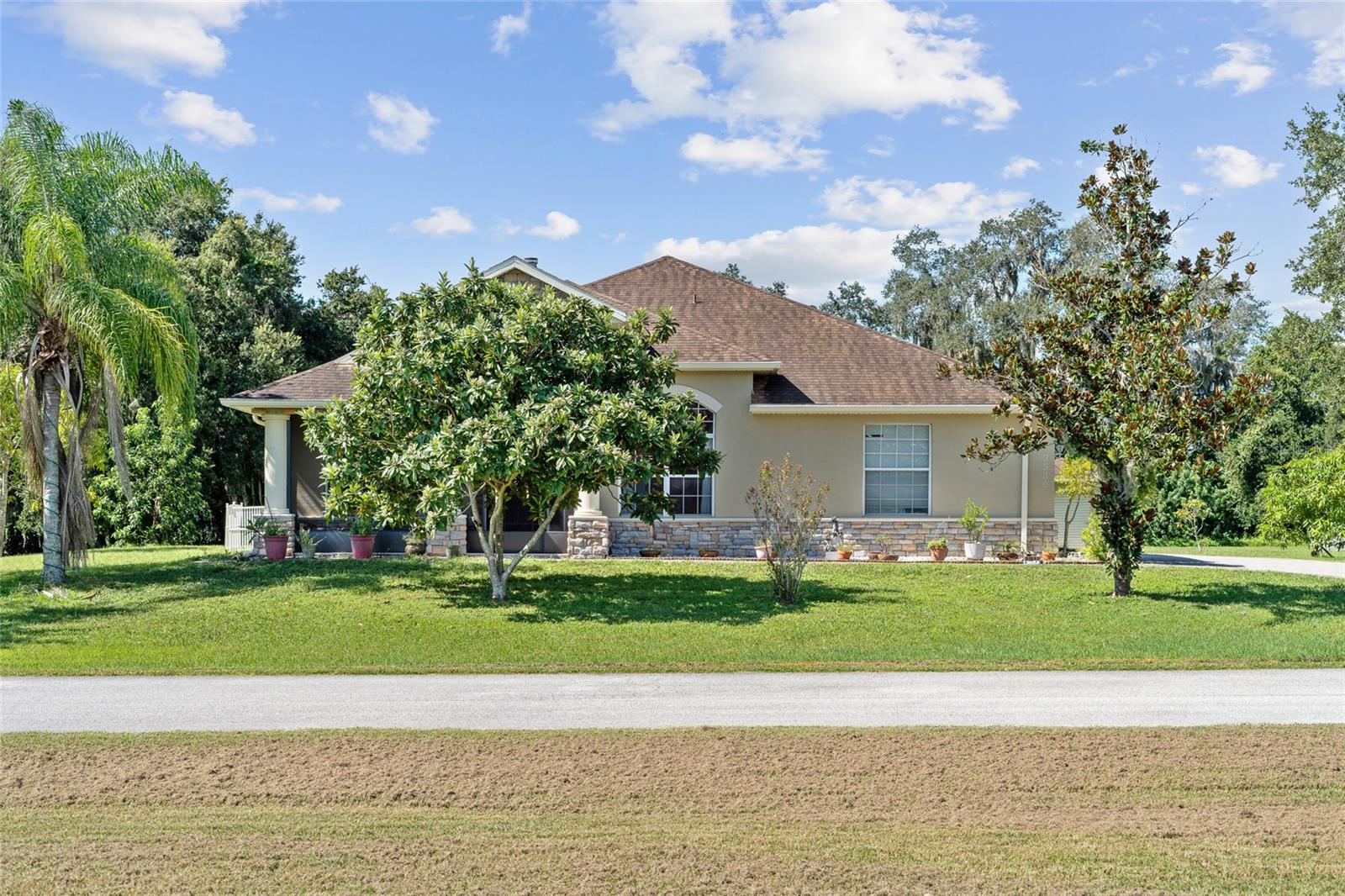 Welcome to Kings Cove where homes are seldom available. This stunning custom-built home offering 3 bedrooms, 3 full baths, and a thoughtfully designed split floor plan sits on a 1 acre lot. From the moment you arrive, the winding driveway and elegant entryway with crown molding set the tone for this exceptional property.
Inside, you’ll find 12-foot ceilings and expansive living spaces, including a grand living room with a wood-burning fireplace centerpiece that serves as the perfect focal point for gatherings. The chef’s kitchen is a true showstopper with an upgraded island range, stainless steel chef’s hood, a butler pantry with wet bar and wine rack leading to your private dining room and a wide-open layout ideal for entertaining. A private dining room and a flexible office/flex room with an adjoining alcove (easily convertible to a 4th or even 5th bedroom) add even more versatility.
The home also features a spacious interior laundry room with sink, a screened front lanai, and an enormous screened rear lanai overlooking the 1-acre lot. Outdoors, enjoy your own slice of paradise with multiple fruit-bearing trees including mango, papaya, banana, and more.
Practical updates include a 2018 roof and 2019 HVAC system. Nestled within a small, gated community where no two homes are alike, this property offers privacy, character, and a welcoming neighborhood feel. Homes here rarely come available, making this a unique opportunity to own a true gem that combines convenience with a peaceful lifestyle—just around the corner from everything you need.