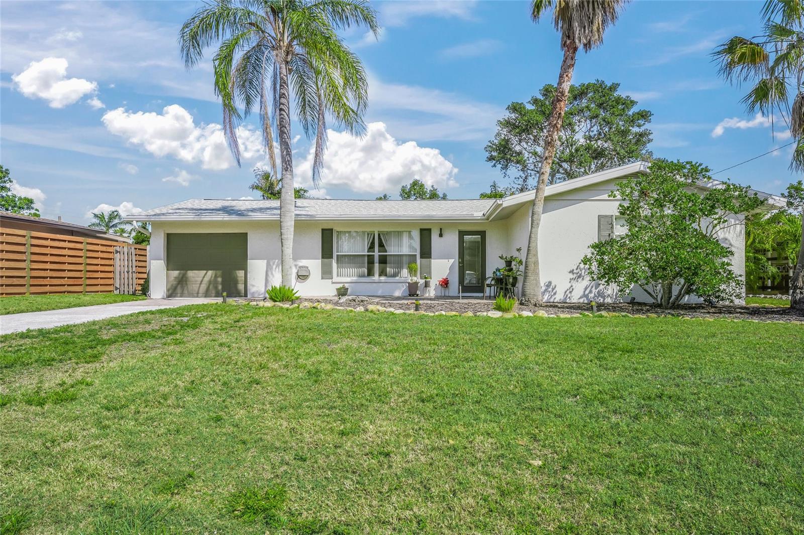 You are in luck! Chic Coastal Living is now possible, right in the Heart of Sarasota!
Nestled in the desirable South Gate community, this impeccably updated home blends modern elegance with timeless charm. From the moment you arrive, you’ll be captivated by its pristine curb appeal, accentuated by lush landscaping and swaying palms. Step inside to experience an airy, sun-drenched interior with stylish finishes and thoughtful renovations from floor to ceiling.
The open-concept living area features a newer roof, newer HVAC, newer hot water heater, luxury vinyl plank flooring, fresh neutral tones, and a stunning accent wall that adds character and depth to the space. A wall of PGT replacement windows bathes the home in natural light, enhancing the warm and welcoming atmosphere. At the heart of the home, the modern chef’s kitchen has been tastefully redesigned with sleek quartz countertops, bold black cabinetry, and an elegant pass-through bar, perfect for entertaining. Stainless steel appliances, upgraded fixtures, and a stylish glass-front display cabinet elevate the space, making meal prep a delight.
The spacious dining area is a true showstopper, boasting vaulted ceilings, dual French doors, and expansive backyard views. Whether hosting an intimate dinner or a festive gathering, this space seamlessly blends indoor-outdoor living. Retreat to the serene primary suite, a tranquil haven featuring plush carpeting, oversized windows, and ample storage. The secondary bedrooms are equally inviting, offering flexible spaces for family, guests, or a home office.
Step outside into your private oasis, where a fully fenced backyard provides both privacy and serenity. The large paver patio is perfect for al fresco dining, shaded under a chic umbrella, while tropical landscaping adds a touch of paradise. Whether enjoying your morning coffee or hosting an evening get-together, this backyard is an entertainer’s dream.
Additional highlights include a newer roof, updated HVAC and hot water heater, knockdown finished ceilings, and fresh paint. Situated on a quiet street, this home is just minutes from Downtown Sarasota, St. Armands Circle, and the world-famous Siesta Key Beach—ranked #1 in the U.S.!
Experience Florida living at its finest—schedule your private tour today before this gem is gone!