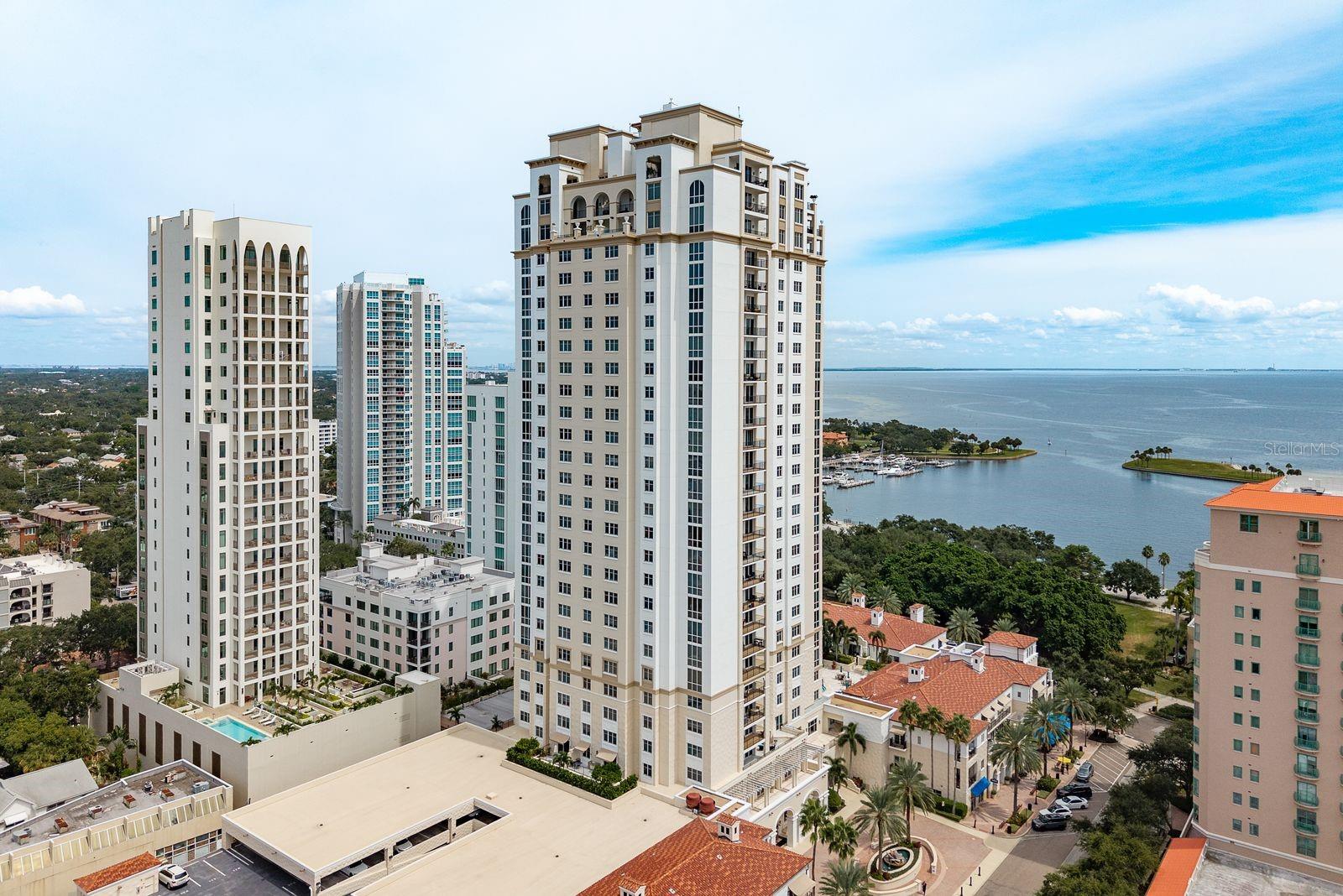 Perched high above the city, this stunning corner residence at Parkshore Plaza delivers an unparalleled luxury living experience in the heart of downtown St. Petersburg. Perfectly situated along vibrant Beach Drive, this home offers breathtaking views of Tampa Bay, The Vinoy resort, the downtown St. Pete skyline, and even downtown Tampa – all visible from your living room. From your private balcony, you’ll enjoy a front-row seat to expansive skyline scenery. Inside, the open-concept floor plan showcases floor-to-ceiling windows that flood the space with natural light and capture panoramic water and city views. The spacious kitchen is perfectly positioned to take in the scenery and features plenty of room for a breakfast table for casual dining. The area to the living room offers flexibility and can be used as a formal dining room, home office, or den. The expansive primary suite is a true retreat, complete with sliding glass doors leading to the covered balcony where you can take in sparkling city lights and stunning sunrise views. Two walk-in closets provide ample storage with wooden racks, and the luxurious primary bath features dual vanities, a walk-in, glass enclosed shower, and a separate garden tub. Your key fob allows secure access to a private elevator vestibule, an on-site climate-controlled storage unit, and two garage parking spaces. Parkshore Plaza provides 24/7 concierge service and an array of exceptional amenities, including a heated resort-style pool and spa, outdoor kitchen with wraparound seating, two grilling stations, outdoor fireplace, state-of-the-art fitness center with men’s and women’s locker rooms and saunas, private massage room, billiards room, library, business center, conference room, and a social room with catering kitchen. Step outside and you’re just moments away from Beach Drive’s renowned dining, boutique shopping, waterfront parks, walking and biking trails, the St. Pete Pier, museums, and entertainment. This rare offering combines the best of city living with unmatched views and resort-style amenities — the ultimate downtown St. Petersburg lifestyle. ***FRESHLY PAINTED, BRAND-NEW CARPETING IN THE BEDROOMS, JUST POLISHED MARBLE TILE FLOORS***