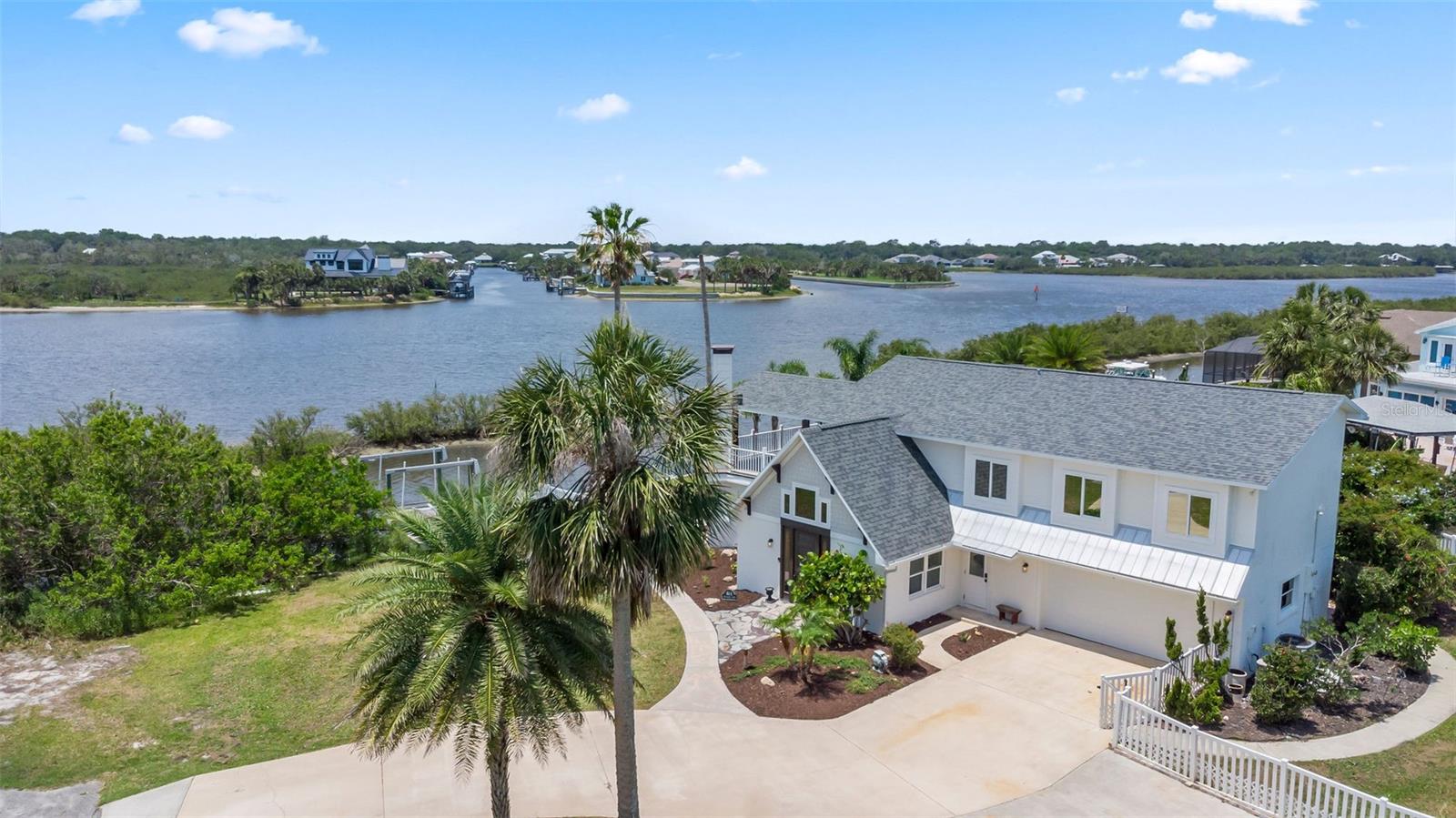 Experience the best of Florida living in this stunning two-story pool home, perfectly nestled on a spacious and private corner lot along a protected stretch of the Intracoastal Waterway. With your own boat lift and over 300 feet of waterfront, this home offers a rare blend of coastal charm, luxury, and convenience. From the moment you arrive, you will be drawn in by the exceptional curb appeal and thoughtfully designed interior. Step inside to find custom kitchen cabinetry that blends style and functionality, a dramatic open staircase that adds architectural flair, and a striking Moroccan chandelier in the living room for a touch of exotic elegance. The first-floor master suite serves as a peaceful retreat, featuring a beautifully updated en-suite bathroom with a freestanding soaking tub, dual vanities, and a spacious walk-in shower with elegant tile work, making it the perfect place to relax and recharge. Upstairs, two generously sized bedrooms provide comfort and privacy for family or guests. Step out onto the second-floor deck—partially covered and ideal for morning coffee or sunset cocktails—while enjoying breathtaking panoramic views of the Intracoastal Waterway, where dolphins play and sailboats glide by. Outside, the private pool invites you to unwind with stunning water views all around. Whether you’re entertaining or enjoying a quiet evening, this backyard oasis delivers unforgettable moments. This exceptional home offers the perfect balance of seclusion and accessibility — just a short golf cart ride to the beach, top-rated restaurants, and vibrant live music venues. Don’t miss your chance to own this extraordinary slice of paradise. Information taken from public and tax records, and while deemed reliable, cannot be guaranteed.