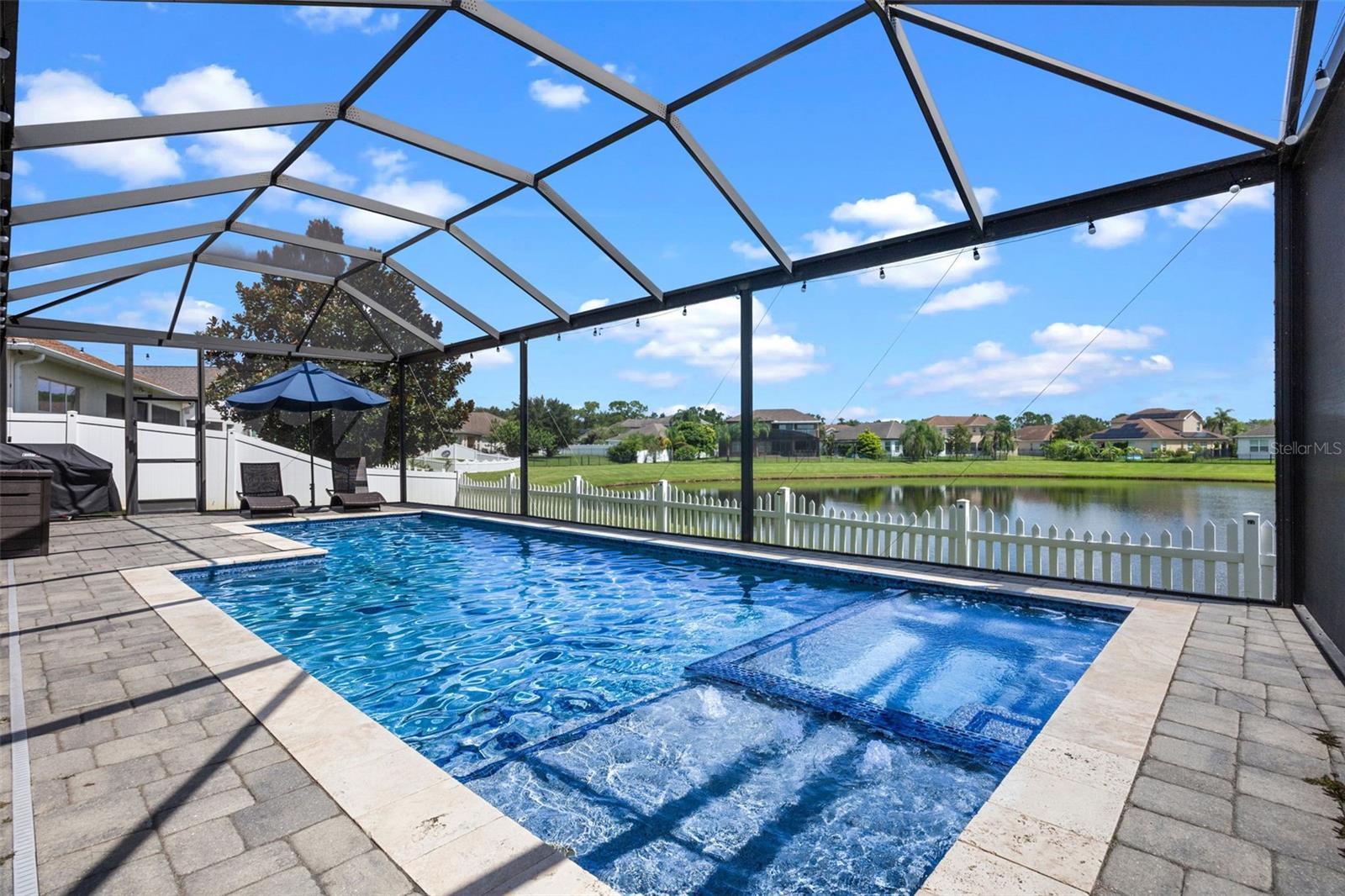 With a $100,000+, huge custom pool, water view and a fully owned whole-house solar system, this 4-bedroom, 3-bathroom home with office and 3-car garage is packed with upgrades that set it apart. From its remarkable curb appeal and welcoming entryway to its tranquil pond views front and back, every inch of this property has been carefully considered to deliver comfort, efficiency, and an outdoor living experience rarely found in homes of this size. The floor plan balances style and function. A foyer accented by crown molding and decorative arches leads into a cozy front living room with fireplace and mantle, which flows into the formal dining room for elegant entertaining. Just off this space, the office is perfectly situated for work or quiet focus. Toward the back of the home, the family room connects seamlessly to the kitchen and breakfast nook, all framed by large windows showcasing the pool and pond. The kitchen has been updated with a new refrigerator, microwave vented to the exterior, and dishwasher (all 2023), plus a washer (2021), a hybrid water heater (2020), and a brand-new interior and exterior AC system (2025). The primary suite captures sweeping views of the pool and pond, with the ensuite bathroom offering a private retreat complete with adult height granite counters, a soaking tub, a separate shower, and a private water closet. Secondary bedrooms are generously sized, and bathrooms also feature granite finishes, keeping a consistent level of quality throughout. Outdoors is where this home truly shines. The expansive 500-square-foot covered patio opens to the showpiece salt water pool built with PebbleTec finish, LED lighting, smart controls, a four-foot shallow end, a six-foot deep end, and a sunken jacuzzi. Both the pool and jacuzzi are electrically heated, ensuring year-round enjoyment. Fully fenced and positioned to take in breathtaking sunrises, the backyard is a destination of its own. Beyond the finishes, the home’s upgrades deliver peace of mind and efficiency. The exterior was freshly painted in 2023 with high-quality Sherwin Williams paint, while a smart sprinkler system and alarm system add convenience and security. The owned solar system is a standout feature, bringing the electric bill to under $100 during the hottest Florida months and an incredible $0 for the rest of the year. Water quality is also a highlight, with a fully owned whole-house water filtration system plus a reverse osmosis system at the kitchen sink, delivering clean, crisp water throughout the home. Combined with the nearby new fire station that helps reduce insurance costs, the savings and lifestyle here are as impressive as the upgrades. Set within a gated community offering a pool and playground, this property also boasts an exceptional location close to schools, with quick access to 417 and the Turnpike. Orlando International Airport and Lake Nona’s Medical City are less than 15 minutes away, making this a home that combines everyday practicality with luxury living. 4445 Biscayne Breeze Way is more than just a house—it is a showcase of efficiency, comfort, and outdoor living at its finest, highlighted by one of the most magnificent pools you’ll find.