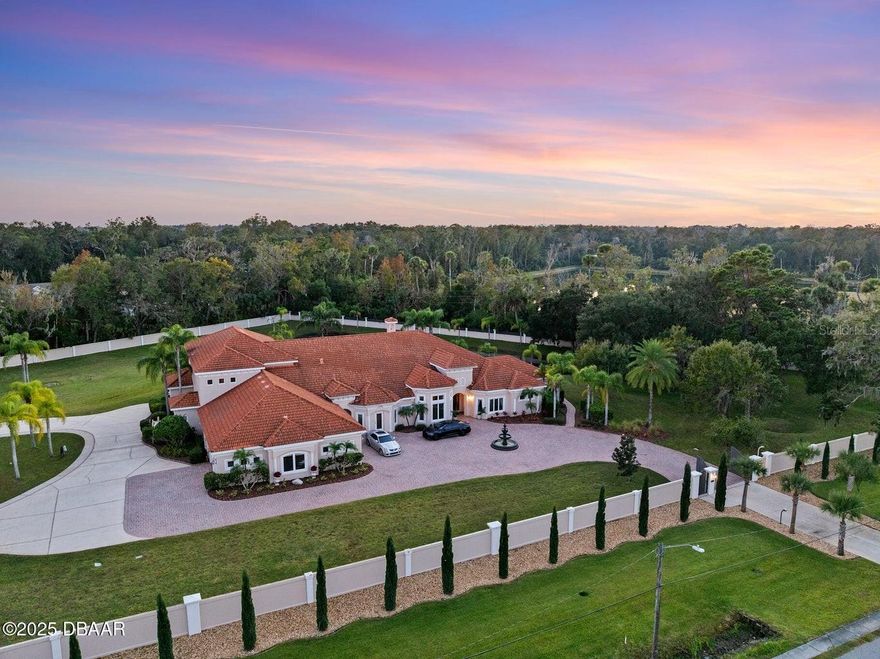 Welcome to 602 Tomoka Avenue — a gated, custom-built estate nestled on 3.39 acres in the heart of Ormond Beach. This one-of-a-kind residence offers over 8,000 sq ft of luxurious living space, thoughtfully designed for comfort, privacy, and grand-scale entertaining. Step through the handcrafted wood entry door into a foyer that sets the tone for the entire home: soaring ceilings, marble floors, accent columns, and a double-sided gas fireplace create a dramatic yet inviting ambiance. The formal living and dining rooms flow seamlessly into a spacious family room with built-ins, coffered ceilings, and direct access to the screened lanai and pool. The chef's kitchen is a showpiece, featuring GE Monogram appliances, a 6-burner gas range with grill, granite countertops, custom cabinetry, and a breakfast bar that opens to a sunlit nook. A full-size butler's kitchen is discreetly tucked away for seamless entertaining. The master wing is a private retreat with double-door entry, lanai access, and a dedicated executive office. Dual spa-inspired bathrooms offer walk-in tiled showers, jetted tubs, custom vanities, and oversized closets with built-ins. Two additional en-suite bedrooms are located downstairs, along with a piano room and a guest suite.
Upstairs, take the elevator to a packed theater room with recliners, starlight ceiling, and a projector  a $100K investment in cinematic luxury. A wet bar and additional guest suite complete the upper level.
Outside, enjoy a resort-style pool and spa, summer kitchen, multiple seating areas, and a tranquil private lake with a fountain. The property includes a 4-car garage, an RV garage with guest quarters (full kitchen and bath), and is fully enclosed by a concrete privacy wall with gated entry.
No detail was overlooked in this architectural masterpiece, experience the pinnacle of Ormond Beach living.