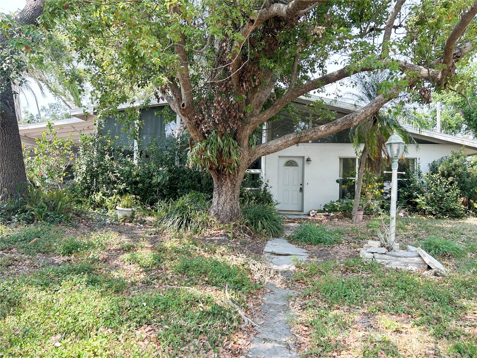 Mid-century modern home near siesta key in sought-after South Gate. Enjoy coastal town vibes in this light-filled 3BR/3BA! This home features an attached mother in-law suite on a separate quarter of the house, equipped with its own bathroom and separate indoor/outdoor entrances. Perfect for guests, renters, or doubles as a study den. Contains tile flooring throughout, cedar-lined closets, a cozy wood-burning fireplace, large vaulted ceilings and an air-conditioned front sunroom. Recent upgrades include a new roof (2024), new A/C, and new washer & dryer. The kitchen is equipped with a Jenn-Air cooktop. The wooded lot is shaded by beautiful oak trees and includes a backyard storage shed. Fantastic location—1 mile to the water, close to schools, shopping, dining, and just minutes from Siesta Key Beach!