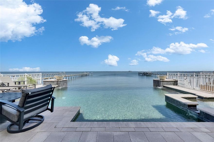 Experience luxury coastal living in this breathtaking Spanish Mediterranean home, perfectly positioned in an exclusive gated community to capture UNOBSTRUCTED PANORAMIC VIEWS of Tampa Bay, St. Petersburg and the Skyway Bridge. As you step through the newly installed custom front door, you're immediately drawn to the show-stopping heated infinity-edge pool and spa that visually blend into the sparkling waters beyond.  From nearly every room, enjoy mesmerizing, wide open waters views. A daily reminder of the beauty and serenity this home offers.  Whether you are lounging by the pool, dining al fresco outside the covered outdoor living area, or relaxing on one of the many private balconies, you'll have a front-row seat to the SPECTACULAR SUNSETS that paint the sky in brilliant shades of orange, pink, and gold.  The OUTDOOR KITCHEN completes the perfect setting for unforgettable evenings spent with family and friends. Inside, the elegance continues with a formal dining room and a designer kitchen featuring QUARTZITE COUNTERTOPS, custom backsplash, solid wood cabinets,  butler's pantry, and premium THERMADOR AND SUB-ZERO appliances, including a professional gas range. Wine connoisseurs with certainly enjoy the wine cellar off the kitchen. The main floor also includes a spacious bedroom with full ensuite bath--ideal as a second primary suite--along with a half bath for guests, and a separate private office making working from home a breeze.  The owner's retreat is a true sanctuary with tray ceilings, custom closets, sliders that lead out to a large covered private balcony, and jaw-dropping views.  The luxurious ensuite bath features dual vanities, a soaking jetted tub, and a walk-in shower.  Three additional bedrooms-each with access to private balconies-giving plenty of space for family or guest, with a full laundry room conveniently located on the same level.  Built with durable and energy-efficient ICF (Insulated Concrete Form) construction, the home has been thoughtfully upgraded with new impact-resistant windows (May 2025), two new A/C units, an on-demand tankless water heater, and a new front door (May 2025). This propoerty qualifies as a SHORT-TERM RENTAL, making it as versatile as it is stunning.  Whether you're searching for your forever home or a high-performing investment, this one-of-a-kind waterfront oasis delivers on every level. Easy commute to downtown Tampa (22 miles) and Tampa International Airport (27 miles)