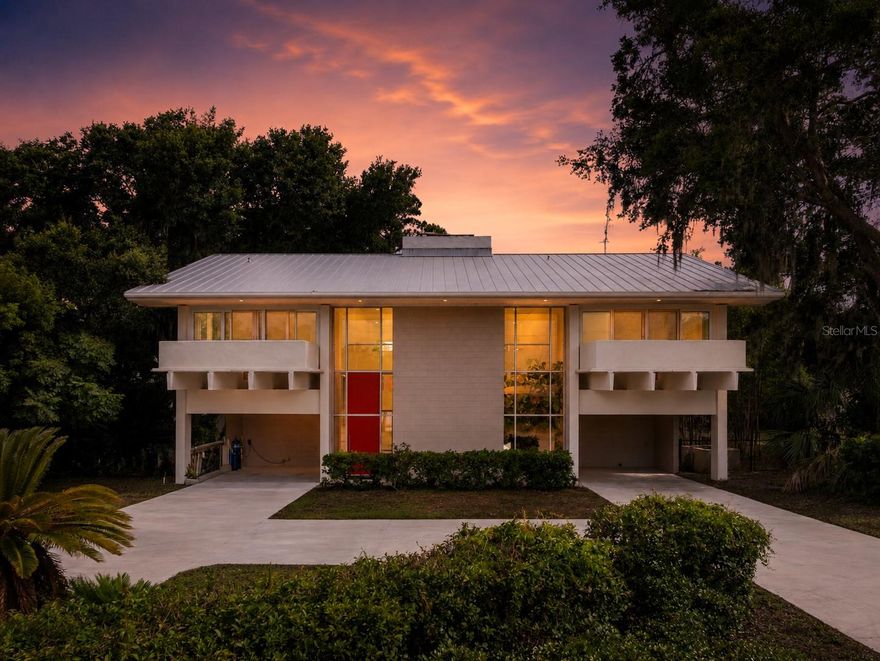 Lakefront living on the Winter Haven Chain of Lakes takes on a completely different feel at The Guest House , a rare Mid-Century Modern residence designed and built by internationally recognized
architect Gene Leedy. Quietly tucked away at the end of a cul-de-sac on the crystal-clear waters of Lake Mirror, the setting feels surprisingly hidden despite being just minutes from shopping, dining, and
convenient access to Lakeland, the Polk Parkway, and Interstate 4 for an easy commute between Tampa and Orlando.
Originally commissioned for Thelma Guest, "The Guest House" is a striking example of Leedy’s signature architectural style, blending precast concrete construction, dramatic cantilevered forms, walls of
glass windows and doors, deep overhangs, and natural light in a way that still feels timeless today. From the street, the design sits perfectly among mature trees and lush landscaping, setting the stage
for what awaits inside.
The layout was thoughtfully designed around openness, symmetry, and connection to the outdoors. A towering two-story glass entry and interior atrium create an immediate architectural focal point, while
the open staircase and original vintage elevator add both character and functionality between levels. The main living spaces are positioned upstairs to maximize natural light and elevated lake views, with
expansive glass overlooking the pool, shoreline, and towering oaks draped in Spanish moss. Nearly every upstairs bedroom and living area opens onto long covered balconies, creating seamless indoor
and outdoor living.
Downstairs offers an entirely different experience with additional flexible living areas surrounding the central atrium and opening directly to the lakefront grounds and pool area . The heated salt-filtered pool
feels perfectly integrated into the original architecture, framed by Leedy’s iconic double “T” beam design and expansive covered patios that naturally extend the living space outdoors. The clean
geometry, broad overhangs, and shaded entertaining areas create a resort-like atmosphere that feels both private and connected to the lakefront setting.
The property itself offers direct frontage on beautiful Lake Mirror , known for its clear water, scenic shoreline, and access to the larger Winter Haven Chain of Lakes — a connected system of more than
20 lakes popular for boating, skiing, fishing, waterfront dining, and exploring by water. A lightly used public boat ramp located immediately next door makes launching effortless without sacrificing usable
shoreline space on the property itself.
Additional highlights include solar panels, tasteful modern updates, integrated storage and closet systems true to the Mid-Century aesthetic, two covered carports, circular drive, low-maintenance
landscaping, and no HOA restrictions. Rarely does a home combine architectural significance, true Chain of Lakes waterfront living, privacy, and Central Florida convenience in such a compelling way.
The Guest House is more than a lakefront residence — it is a piece of Winter Haven architectural history.