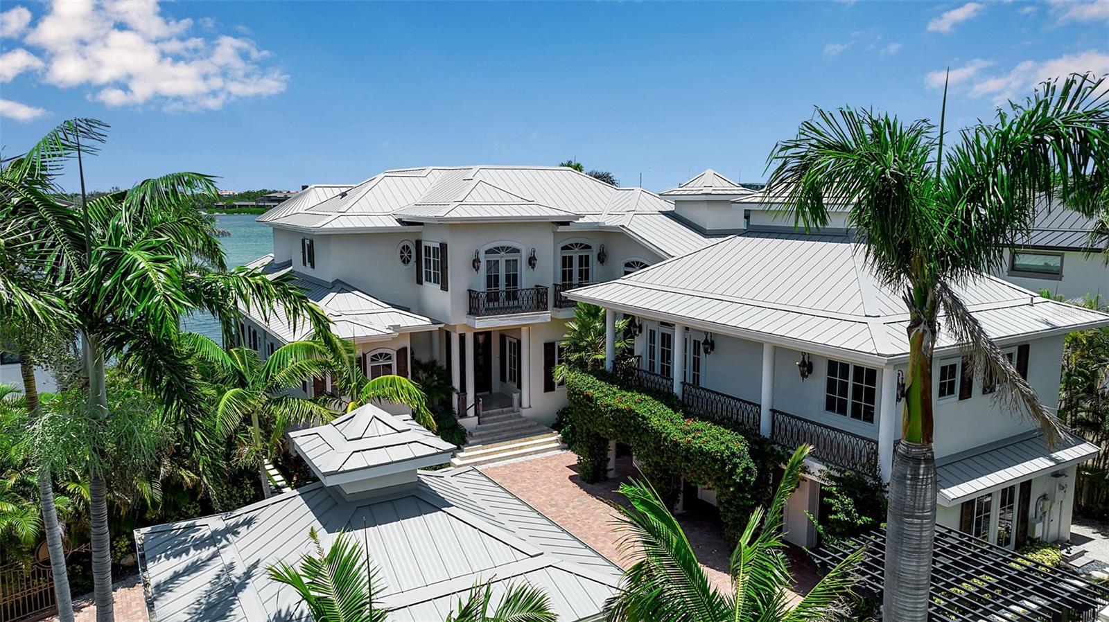 A Coastal Masterpiece in Lido Shores
Tucked away at the end of a quiet cul-de-sac in the prestigious Lido Shores community, this extraordinary coastal estate redefines luxury living with a seamless blend of British West Indies design and modern sophistication. Boasting over 110 feet of prime waterfront on New Pass, the property offers direct, deepwater access to the Gulf of Mexico and Sarasota Bay—making it a dream for boating enthusiasts.
Winner of HGTV’s 2021 Ultimate House Hunt for waterside homes, this gated retreat sits among some of the most iconic and architecturally notable residences in Sarasota. Residents of Lido Shores enjoy private, gated access to the serene sands of North Lido Beach, just moments away.
Crafted in 2013 and designed by renowned architect Brian Phipps, the five-bedroom, smart-enabled home was built for effortless living and entertaining. Two spacious primary suites—one on each level—offer flexibility and privacy, while the elevator connects both floors for optimal convenience. Dramatic 12-foot ceilings, expansive walls of glass, and multiple covered terraces create an immersive indoor-outdoor experience that captures the tranquil beauty of the waterfront.
The great room is a study in relaxed elegance, featuring custom built-ins and a gas fireplace that flows into a chef’s kitchen outfitted with premium appliances, including a Wolf gas range, dual Miele dishwashers, and a 60” Sub-Zero refrigerator/freezer. A dedicated second-floor guest wing offers two bedrooms, two baths, and a kitchenette—ideal for hosting in comfort and style.
Upstairs, the main owner’s suite is a private sanctuary complete with a lounge area, wet bar, wine fridge, espresso station, and study—each space opening onto a sweeping terrace with spectacular views of New Pass and the Gulf beyond. Dual walk-in closets and a spa-inspired bath with soaking tub, walk-in shower, and private balcony complete the suite.
Outside, enjoy a resort-like setting with a summer kitchen, heated pool featuring a waterfall and hidden lounging alcove, and an all-weather dock with a 24,000 lb boat lift plus an additional 4,500 lb lift for jet skis. The home is set on three-quarters of an acre, which includes an adjacent, buildable lot transformed into a lush garden oasis with meandering paths, a serene pond, custom lighting, and a cascading waterfall. This unique space offers potential for expansion with a guest house or additional residence.
Located just minutes from St. Armands Circle and downtown Sarasota, this estate offers a rare opportunity to experience the very best of Florida's Gulf Coast living—where architecture, nature, and elegance meet.