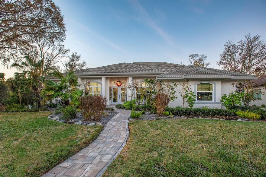 Embrace the best of Florida living in this beautifully renovated Griffon Woods home in Longwood Run, offering over 2,700 square feet of thoughtfully planned space. Every main room opens to the expansive covered lanai with heated pool—perfect for relaxing or entertaining outdoors. The lanai features a pool cage with custom lighting. A bonus extra paved area just outside the screened lanai, ideal for a cozy fire pit, grilling, or simply sitting and watching all the Florida wildlife. Durable engineered hardwood floors flow throughout the entire home, while shellstone tile in the bathrooms and lanai creates a cohesive, sophisticated look. This home features 3 spacious bedrooms, 2 1/2 baths, and a flexible den that can easily be converted into a fourth bedroom. A culinary kitchen featuring a 48” pro-range perfect for any home chef. Walls of windows bathe the interior in natural light. This home was recently updated with impact-rated windows, 3 massive sliding glass doors,  a double front door, and a garage door, adding peace of mind. Enjoy tranquil pond and canal views, lush landscaping, and landscape lighting that enhances curb appeal. With its prime location near the beach, golf courses, pickleball or tennis at Longwood Run Park, and shopping at UTC, this exceptional home puts you in the heart of everything Sarasota has to offer. Don't miss your chance to make it yours!