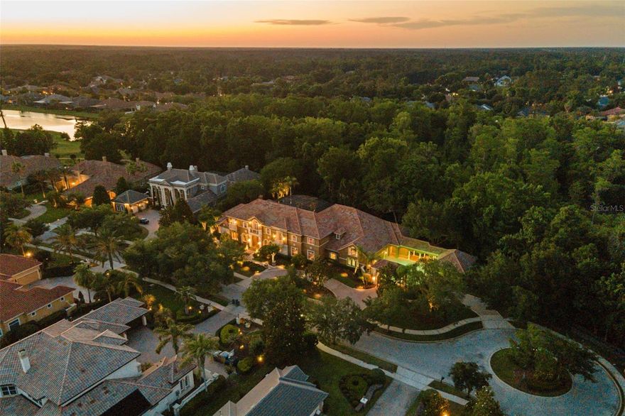 A rare opportunity to own one of the most extraordinary estate residences in Alaqua Lakes. Privately positioned behind the exclusive gates of The Enclave at Alaqua Lakes on a 1.2 acre double lot, this exceptional 12,000-square-foot custom Dave Brewer estate offers unparalleled privacy, luxury, and time-honored craftsmanship throughout. A rare achievement for any builder is when their name becomes synonymous with exceptional quality, timeless design, and uncompromising integrity. In Central Florida, the Dave Brewer name on a custom residence represents exactly that distinction, and this estate is a flagship property of his vast portfolio.  An astonishing 7 bedrooms(6 on the main level), and 7 full baths with 3 half baths, this residence is designed for both grand-scale entertaining and everyday living, and showcases an extensive list of high-end upgrades. Discover elegant travertine flooring, a professionally designed chef’s kitchen with double ovens, dual Sub-Zero built-in refrigerators, two dishwashers, a six-burner Dacor gas cooktop, an oversized center island with freezer drawers, and an expansive walk-in pantry/prep kitchen complete with additional refrigeration and prep space. The thoughtfully designed floor plan features a dedicated children’s wing with a private play area, an upstairs nanny or guest suite, and a luxurious owner’s retreat with a beverage center, spa-inspired bath, and extraordinary custom walk-in closets. A richly appointed executive office with dual custom workstations and adjoining storage rooms enhances the home’s functionality. Exceptional custom details continue throughout the residence, including extensive built-in cabinetry and a spectacular 1,000-gallon saltwater double-sided aquarium serving as a dramatic focal point within the family room and game room. The outdoor living experience is equally impressive, featuring a gated motor court leadng to an oversized 5 car garage, while the rear boasts a resort-style saltwater pool and spa, expansive pavered lanai and entertaining areas, custom summer kitchen, and lush professionally designed landscaping creating a truly private resort atmosphere. This is a one-of-a-kind luxury offering in one of Central Florida’s most sought-after golf and country club communities.  Located just steps from the community’s exceptional amenities, residents of Alaqua Lakes enjoy access to a pavilion, 7-acre park, junior Olympic pool, Har-Tru tennis courts, beach volleyball, basketball courts, multipurpose fields, playground, and social events all within a natural gas community known for its exclusivity and lifestyle. All this and more with incredible proximity to major highways, world-class shopping, dining, attractions, and great schools.  This property may be under audio/visual surveillance.