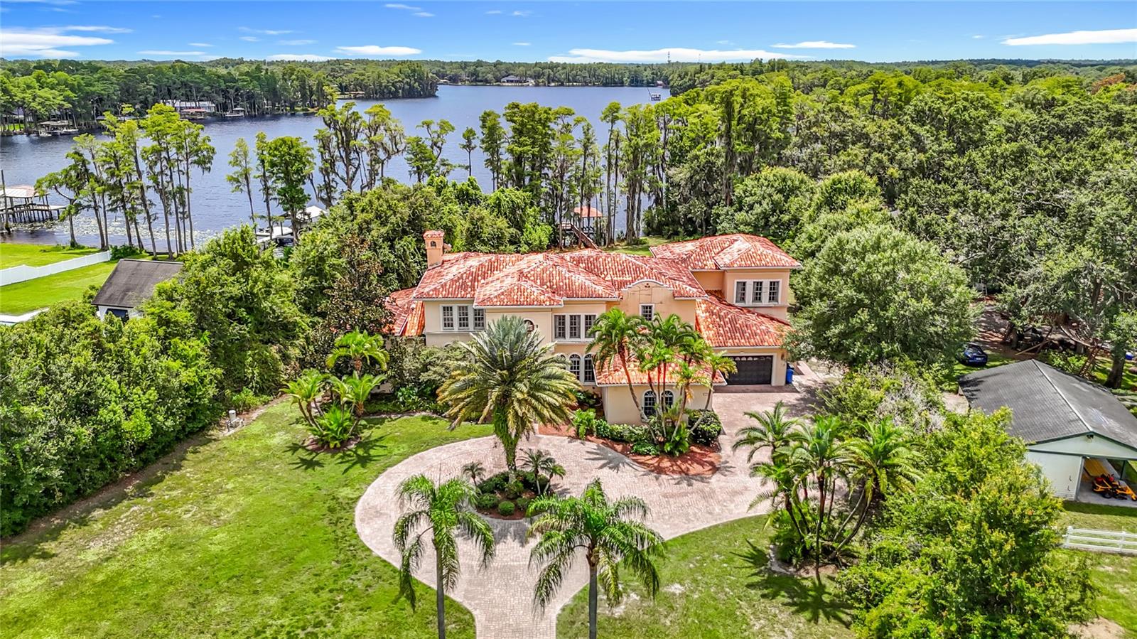 Welcome to an extraordinary lifestyle at 7732 N Mobley Rd, Odessa, FL 33556, a stunning 2.5-acre lakefront estate on ski-sized Lake Pretty, secured by a private gated entry. This custom-built, two-story masterpiece, crafted in 2001, spans 6,367 square feet and offers 5 bedrooms, 6.5 bathrooms, and an attached 4-car garage. Step into a grand foyer with soaring cathedral ceilings and a custom circular staircase leading to the upper level. The main floor boasts elegant separate living and dining rooms, while the open-concept kitchen and family room create a warm ambiance with a fireplace and temperature-controlled wine room. The gourmet kitchen shines with wood cabinets, granite countertops, a Sub-Zero refrigerator and freezer, a stainless steel 6-burner cooktop with grill, a walk-in pantry, and a butler’s pantry. The first-floor master suite is a serene retreat, featuring a sitting area, morning kitchen, fireplace, enormous closet, and a luxurious primary bathroom with dual sinks, a garden jet tub, and a floor-to-ceiling shower/steam room. Convenience abounds with laundry rooms on both floors, while the second floor offers a media room and a versatile bonus room. Outside, a sprawling paver patio surrounds the pool and spa, offering breathtaking views of Lake Pretty. Covered dock with lift, electric and plumbing with boat ramp also. Currently zoned for A-Rated Northwest Elementary School and Steinbrenner High School. Within 20 miles, explore thrilling attractions like Busch Gardens Tampa Bay (16 miles) for exhilarating rides, or immerse yourself in marine life at the Florida Aquarium (18 miles). Relax on the sandy shores of Clearwater Beach (19 miles) or hike the scenic trails of Honeymoon Island State Park (18 miles). Golf enthusiasts will love TPC Tampa Bay (6 miles), and history lovers can wander the vibrant streets of Ybor City (17 miles). This Lake Pretty estate combines unparalleled luxury with access to Tampa Bay’s finest destinations, creating a perfect blend of tranquility and adventure. (Home will need new roof and some other repairs.)