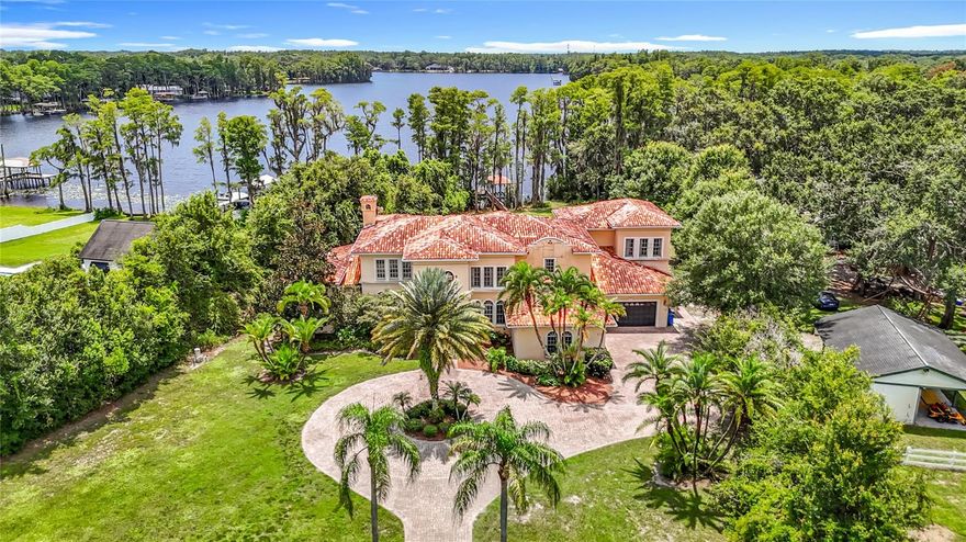 Welcome to an extraordinary lifestyle at 7732 N Mobley Rd, Odessa, FL 33556, a stunning 2.5-acre lakefront estate on ski-sized Lake Pretty, secured by a private gated entry. This custom-built, two-story masterpiece, crafted in 2001, spans 6,367 square feet and offers 5 bedrooms, 6.5 bathrooms, and an attached 4-car garage. Step into a grand foyer with soaring cathedral ceilings and a custom circular staircase leading to the upper level. The main floor boasts elegant separate living and dining rooms, while the open-concept kitchen and family room create a warm ambiance with a fireplace and temperature-controlled wine room. The gourmet kitchen shines with wood cabinets, granite countertops, a Sub-Zero refrigerator and freezer, a stainless steel 6-burner cooktop with grill, a walk-in pantry, and a butler’s pantry. The first-floor master suite is a serene retreat, featuring a sitting area, morning kitchen, fireplace, enormous closet, and a luxurious primary bathroom with dual sinks, a garden jet tub, and a floor-to-ceiling shower/steam room. Convenience abounds with laundry rooms on both floors, while the second floor offers a media room and a versatile bonus room. Outside, a sprawling paver patio surrounds the pool and spa, offering breathtaking views of Lake Pretty. Covered dock with lift, electric and plumbing with boat ramp also.  Currently zoned for A-Rated Northwest Elementary School and Steinbrenner High School.  Within 20 miles, explore thrilling attractions like Busch Gardens Tampa Bay (16 miles) for exhilarating rides, or immerse yourself in marine life at the Florida Aquarium (18 miles). Relax on the sandy shores of Clearwater Beach (19 miles) or hike the scenic trails of Honeymoon Island State Park (18 miles). Golf enthusiasts will love TPC Tampa Bay (6 miles), and history lovers can wander the vibrant streets of Ybor City (17 miles). This Lake Pretty estate combines unparalleled luxury with access to Tampa Bay’s finest destinations, creating a perfect blend of tranquility and adventure.  (Home will need new roof and some other repairs.)