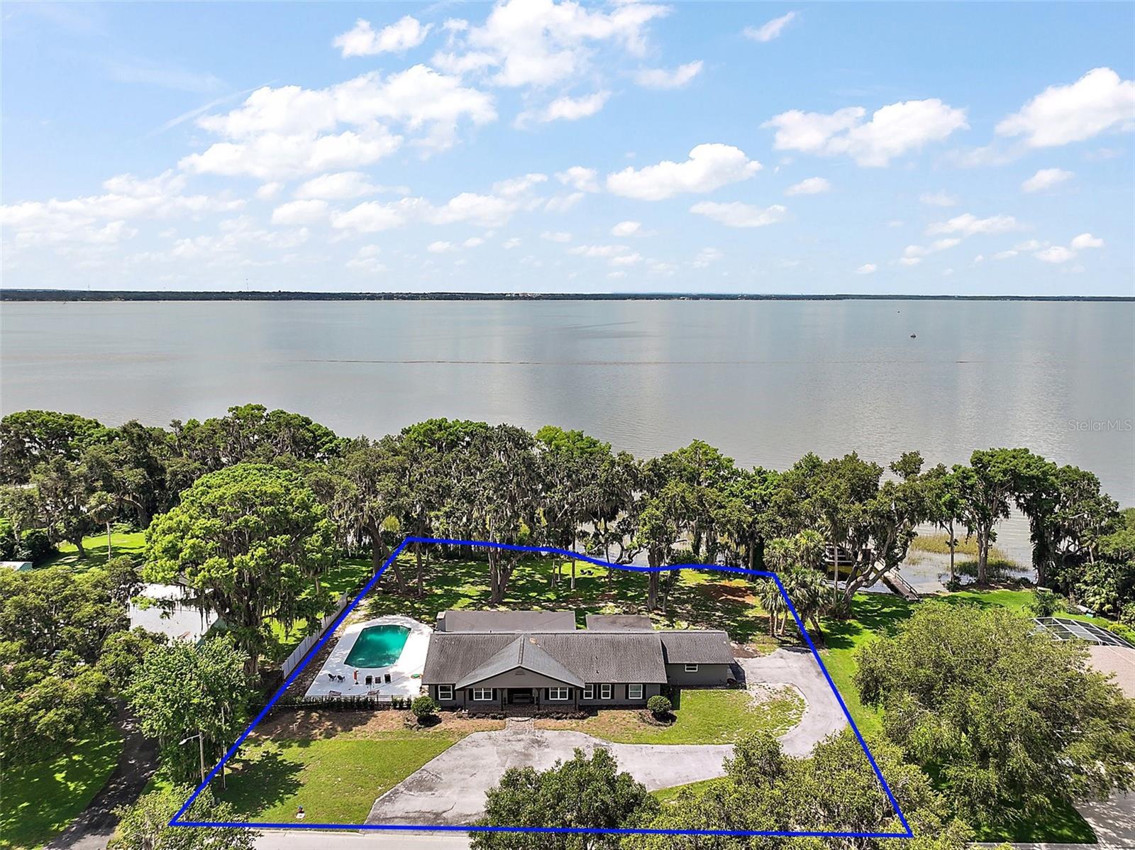 Welcome to this beautifully updated ranch-style lake home nestled on just under an acre, offering the perfect blend of modern comfort and waterfront charm. Located on the sought-after Chain of Lakes, this 3-bedroom, 3.5-bath retreat features an open-concept layout with seamless flow between the kitchen, dining, and living areas ideal for entertaining and everyday living. The heart of the home is the warm and inviting kitchen, thoughtfully outfitted with an expansive 11x4 island, a beautifully Italy crafted Verona electric range, a charming pot filler, built-in wine rack, and a convenient mini fridge. Each bedroom features its own walk-in closet and bathroom. Enjoy breathtaking lake views from the expansive 48x15 Florida room, designed to bring the outdoors in. The primary suite boasts a private en-suite bathroom, a custom California closet, and a spacious office complete with a stunning picture window overlooking the water. Recent upgrades include brand-new Pella windows throughout, grand expanded hallway, new interior and exterior paint, new flooring, new base boards, a new insulated garage door, and a 65x40 freshly poured concrete surrounding the pool. The fully fenced backyard is perfect for pets and entertaining while the cleared beachfront area provides easy access to the lake for swimming or launching your boat. Also this home is equipped with exterior security cameras and built-in music speakers inside and out, perfect for peace of mind and effortless entertaining. This home is the complete package ready with room to enjoy every season lakeside.